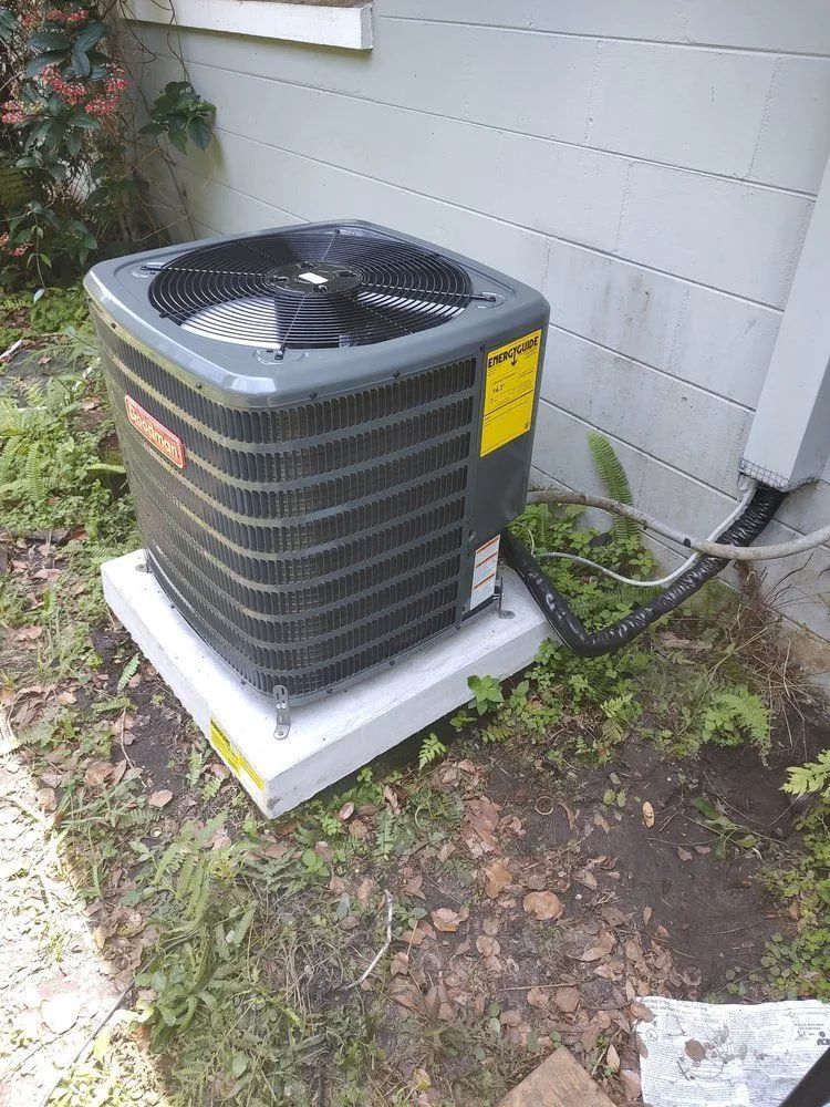 A large air conditioner is sitting outside of a house.