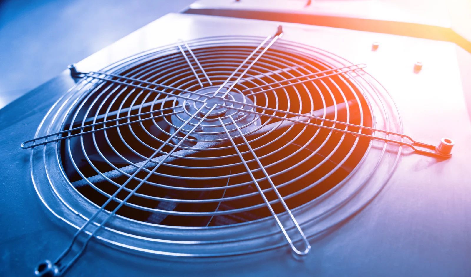 Close-up of a metal cooling fan grill with blue and orange lighting