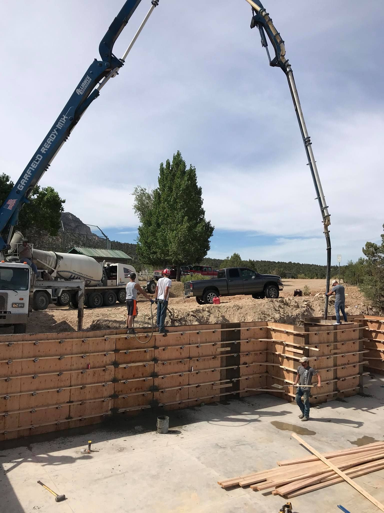A crane is pouring concrete into a wooden wall.