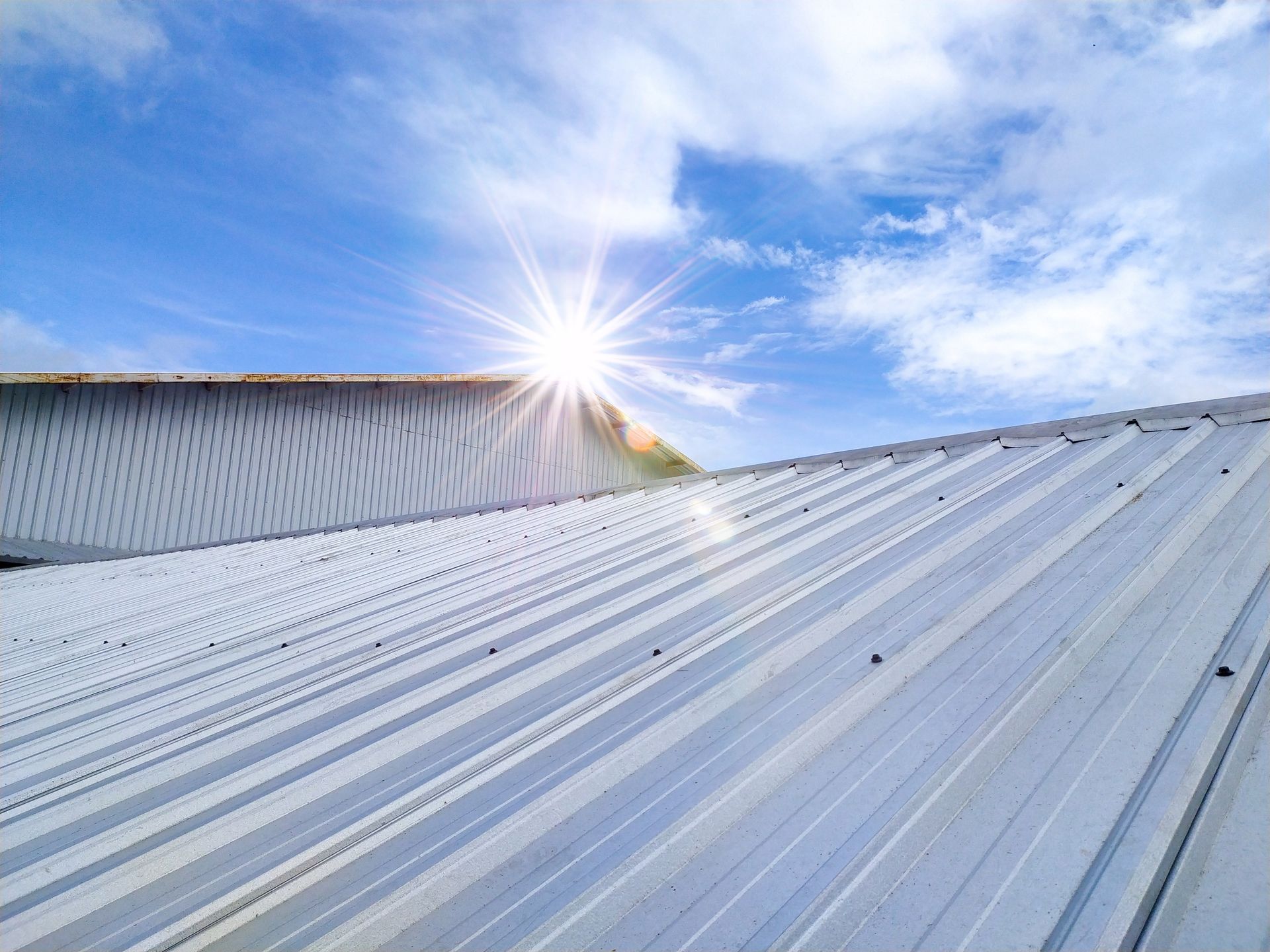 The sun is shining through the clouds on the roof of a building.