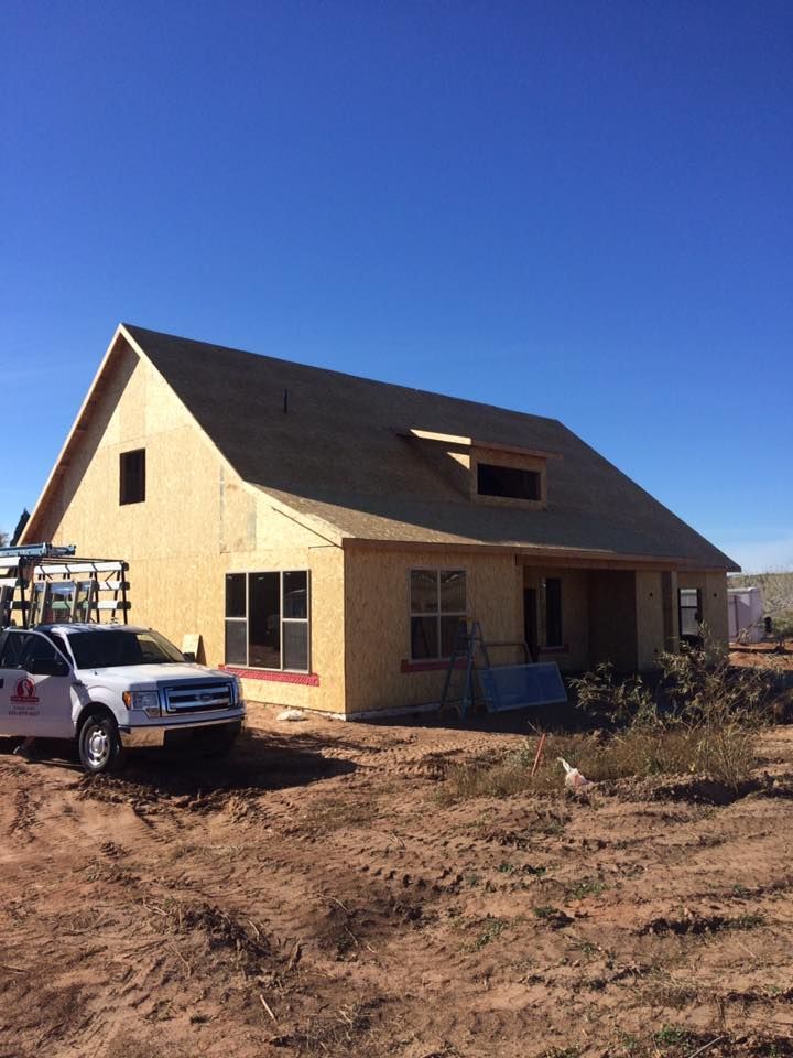 A white truck is parked in front of a house under construction.