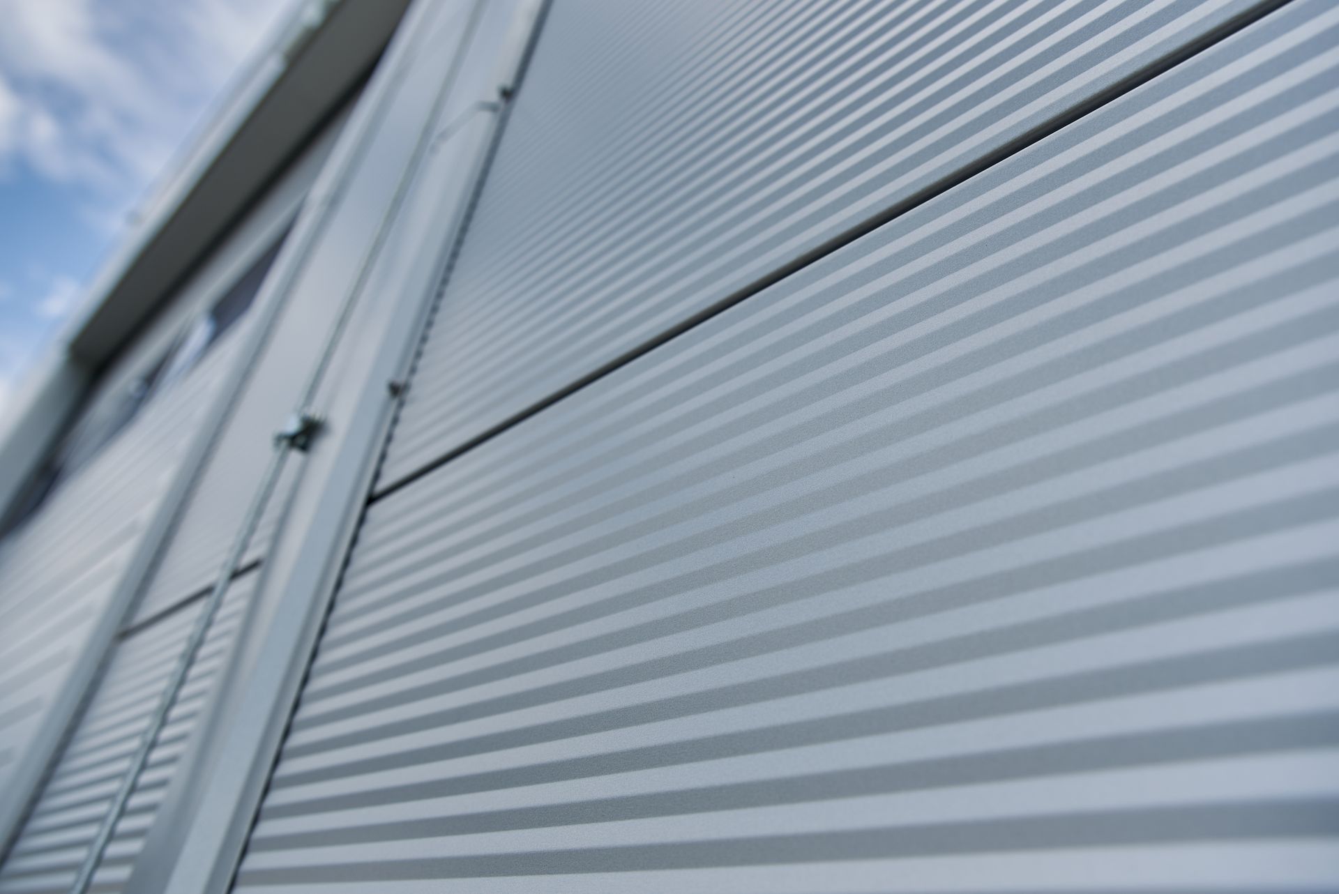 A close up of a metal wall of a building with a blue sky in the background.