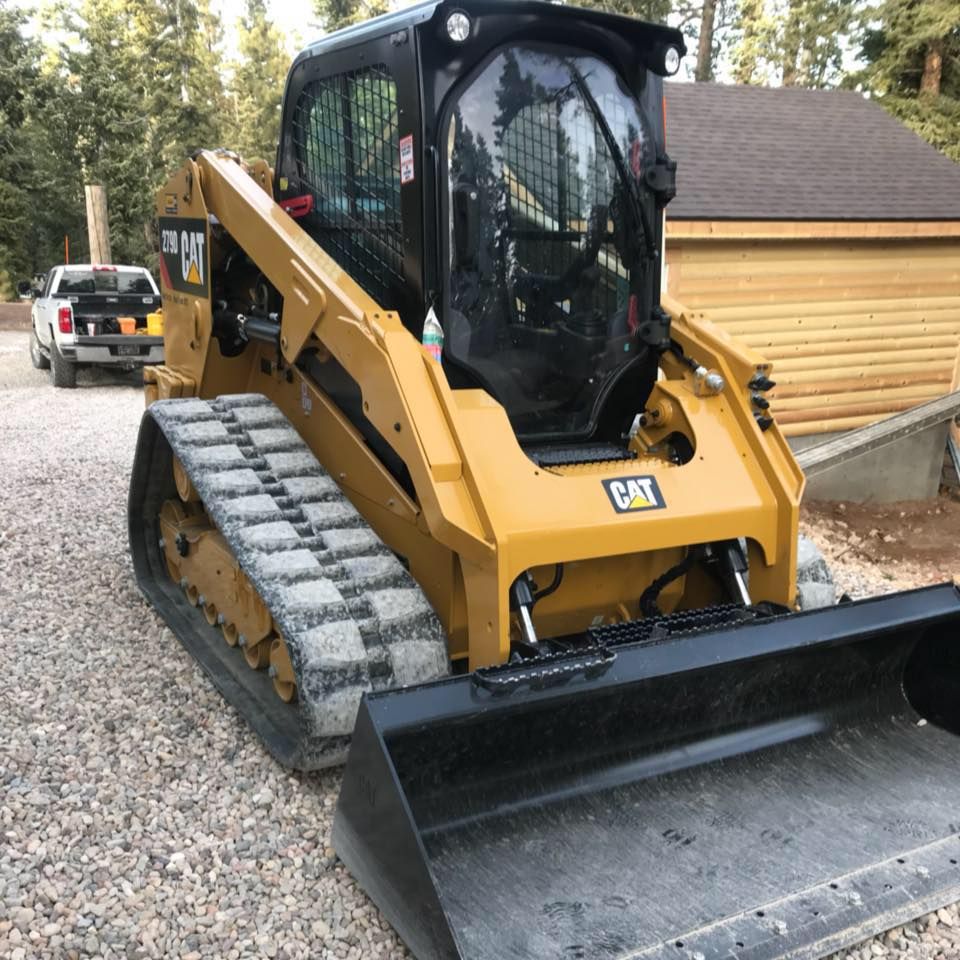 A cat bulldozer is parked in a gravel driveway