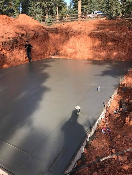 A man is standing on a concrete floor in a hole in the ground.
