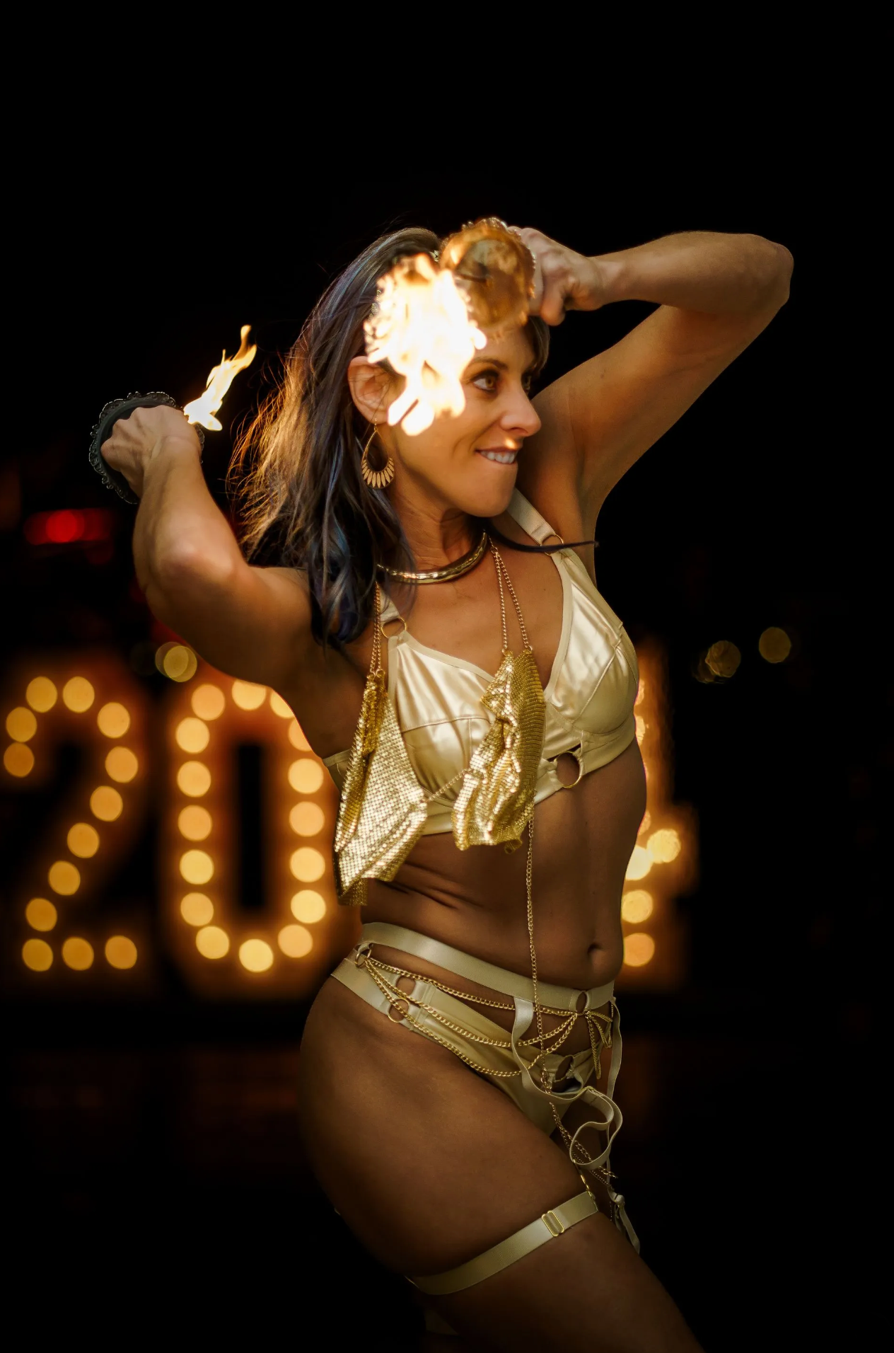 A woman is holding a fire torch in front of a sign that says 20.