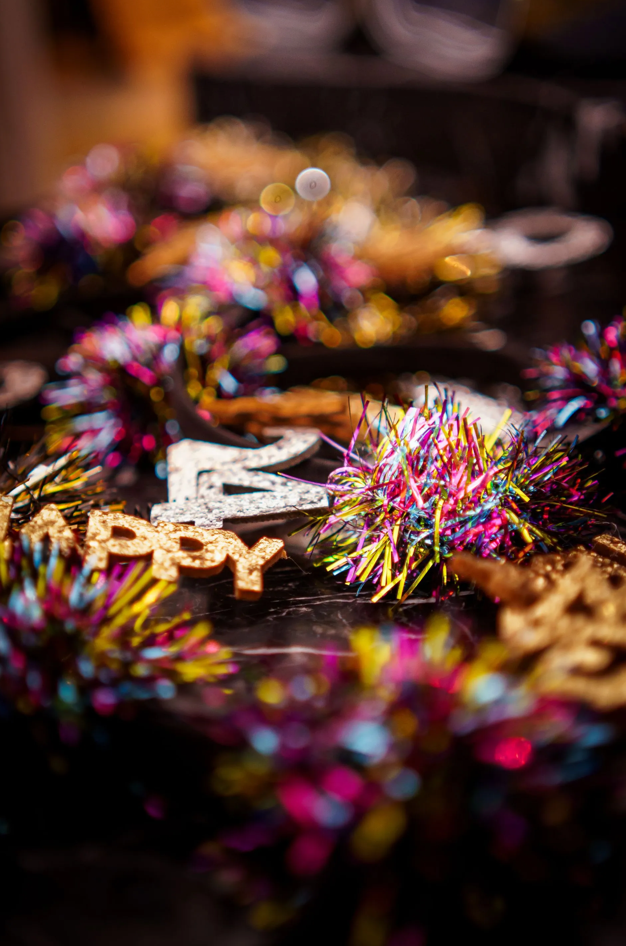 A close up of a birthday cake decorated with confetti and tinsel.