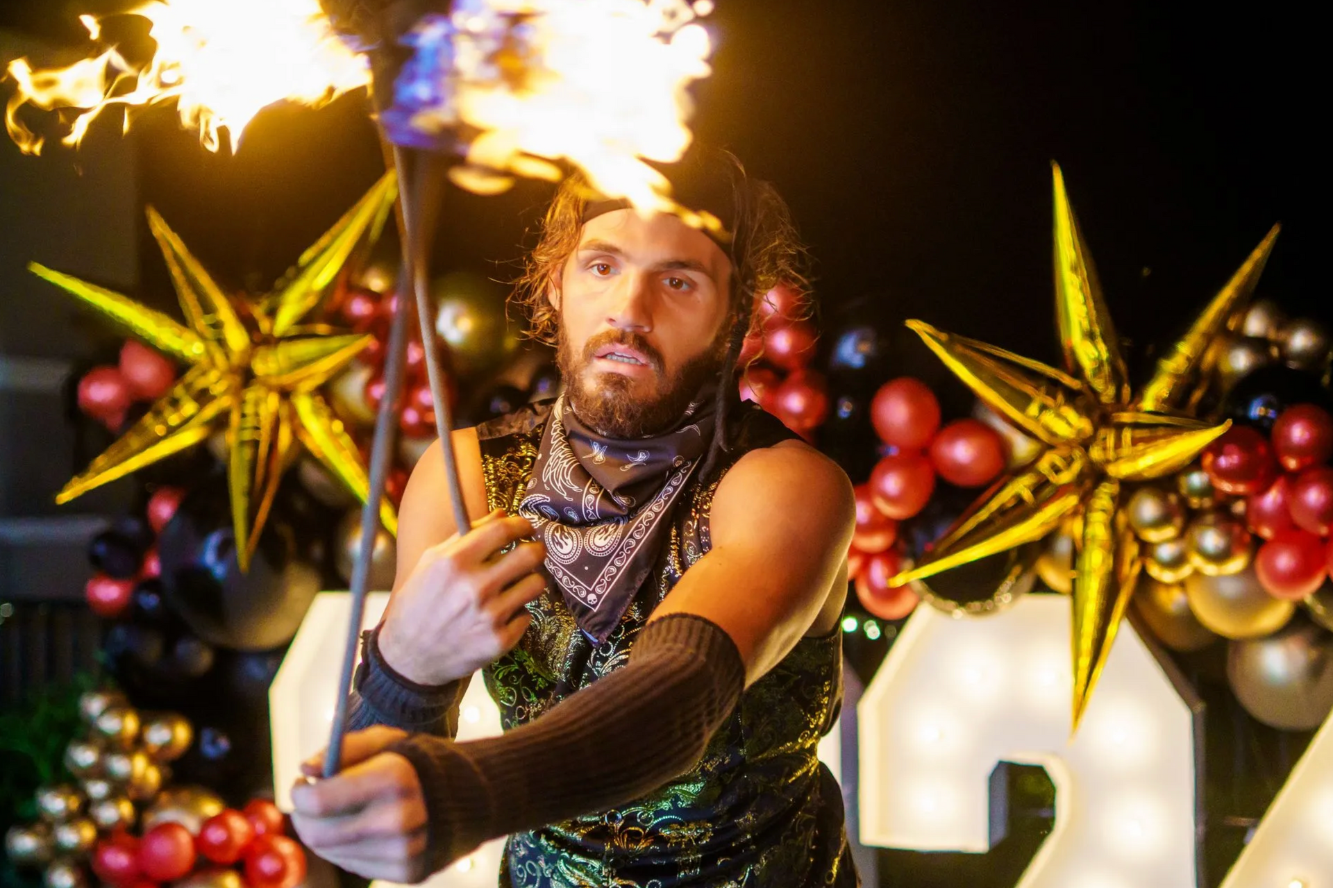 A man is holding a stick with flames coming out of it.