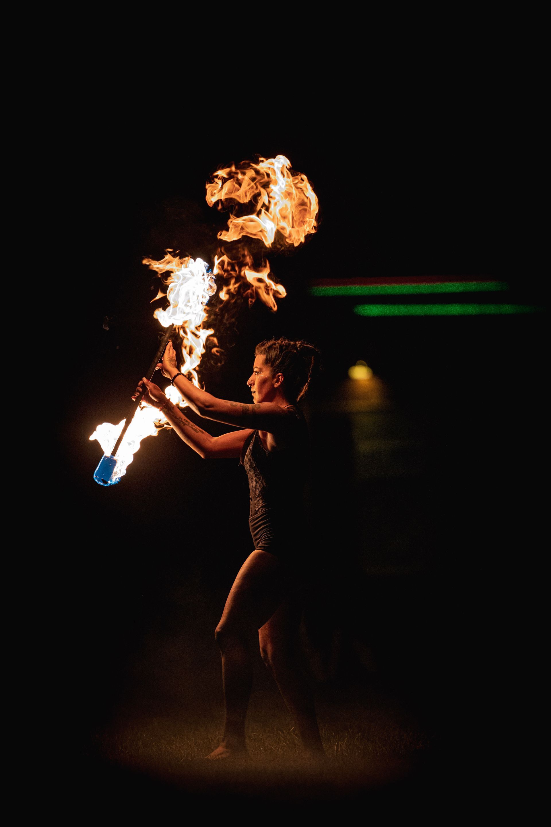 A woman is holding a torch with fire coming out of it.