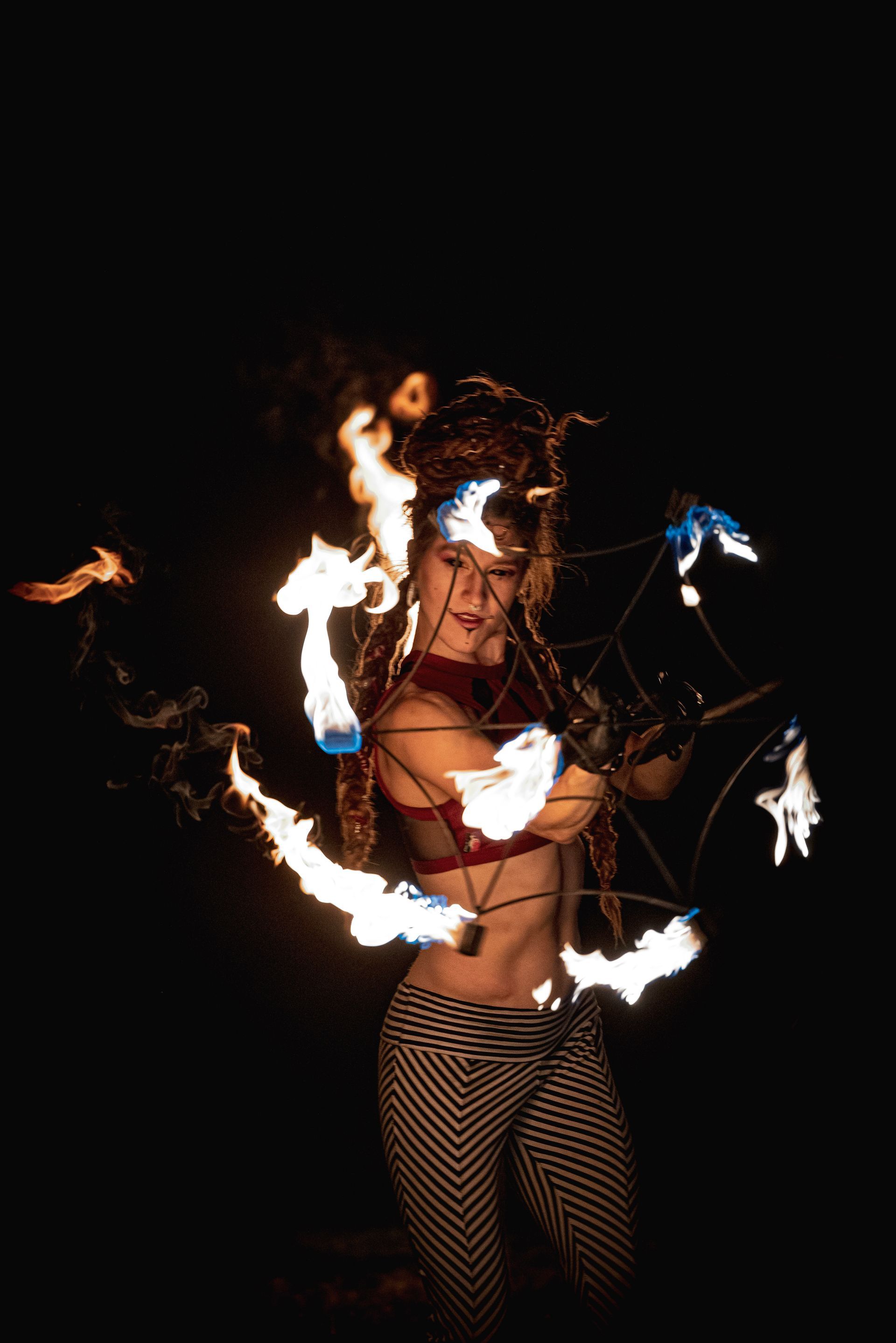 A woman is performing a fire show in the dark.
