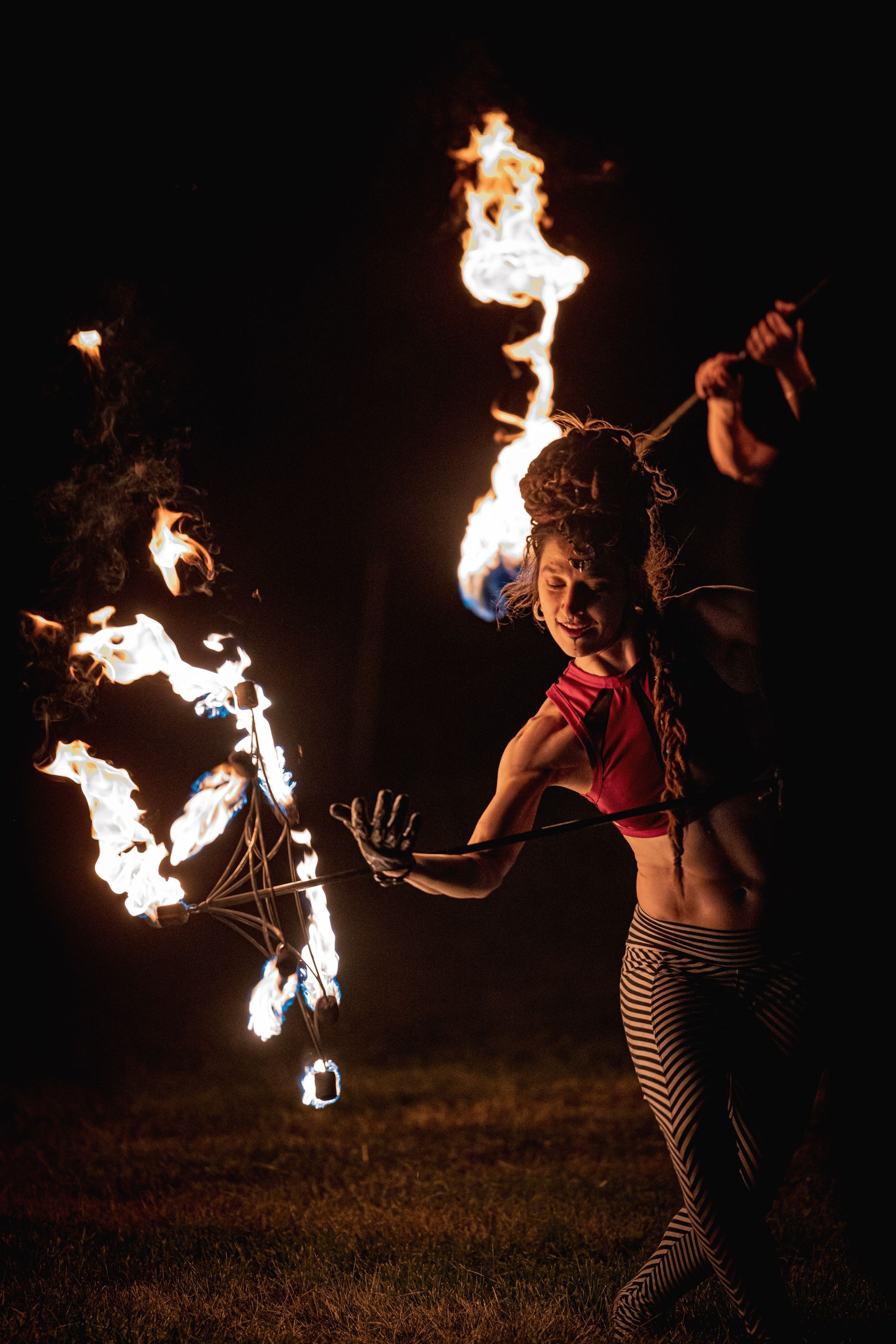 A woman is holding a torch in her hand at night.