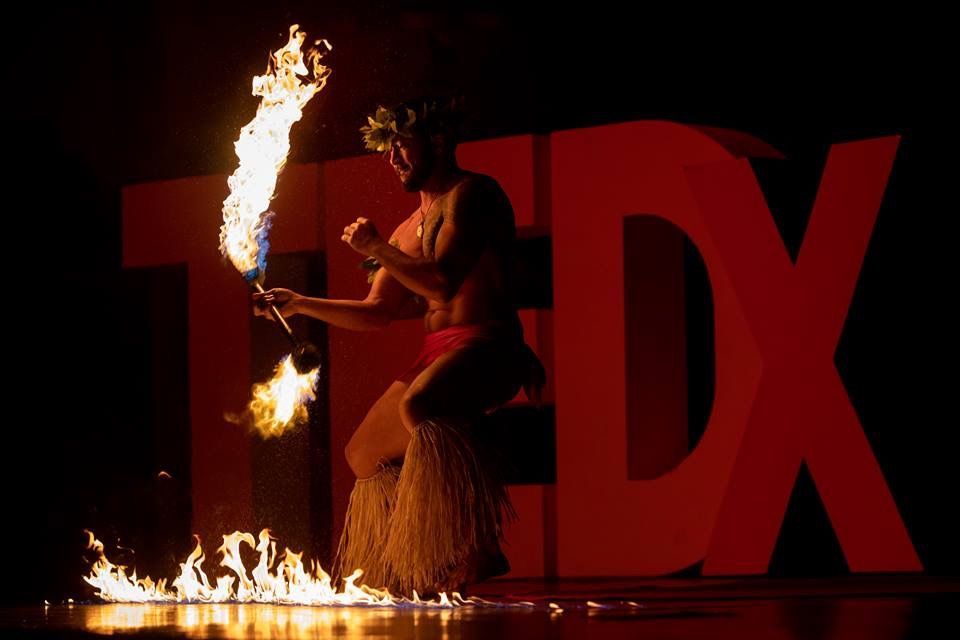A woman is holding a torch in front of the tedx logo