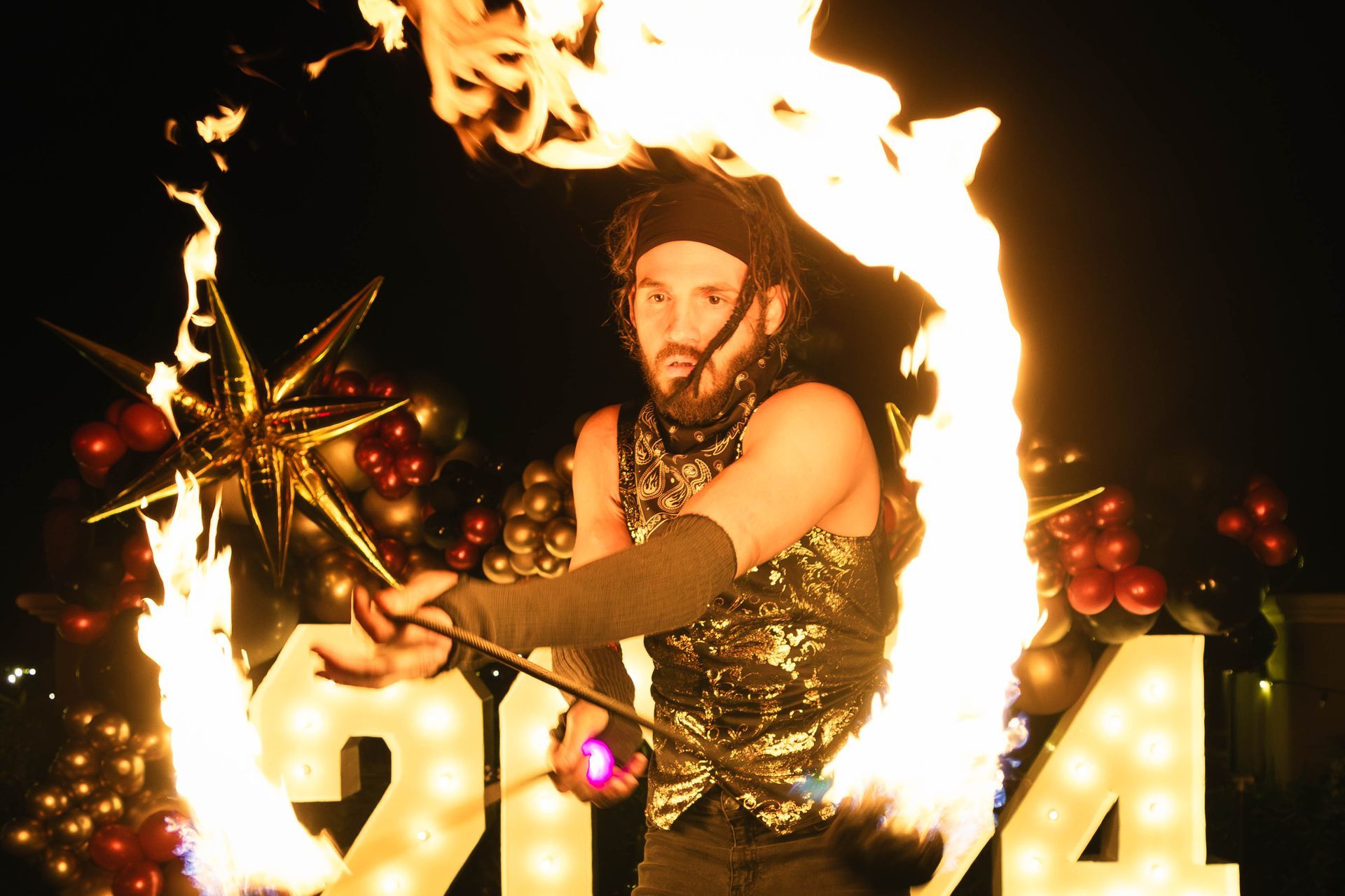 A man is holding a stick of fire in front of a sign that says 2014.