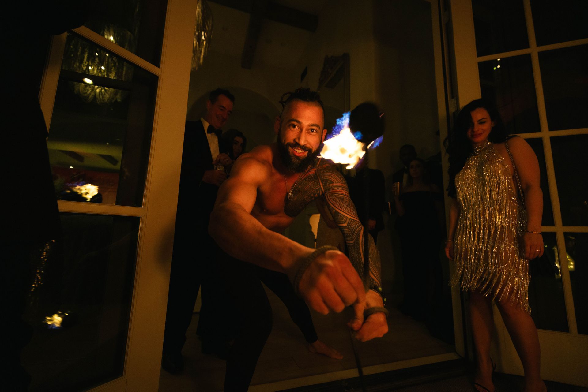 A man without a shirt is dancing in a dark room with a woman in a dress.