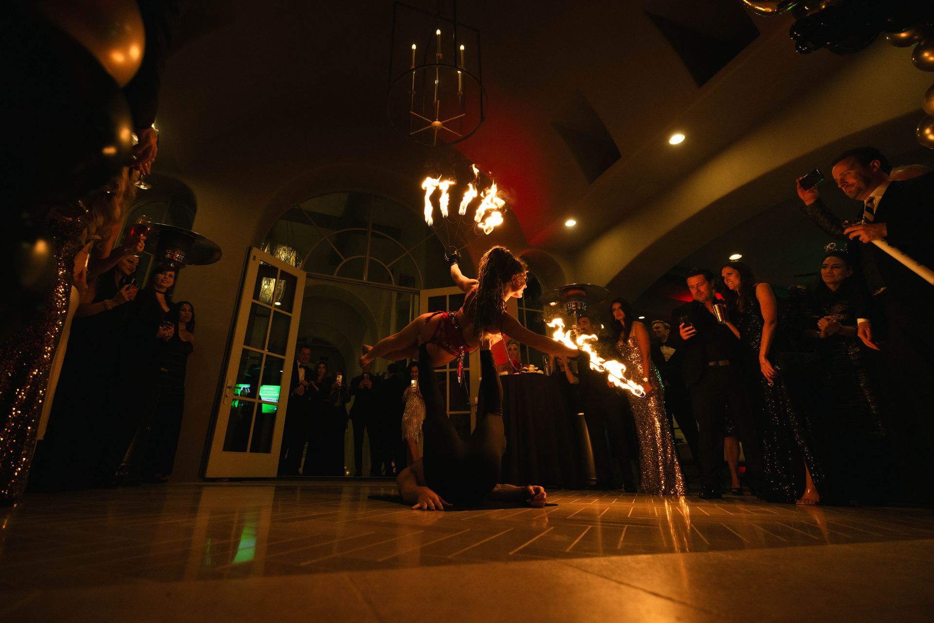 A man and woman performing acrobatic fire at a mansion.