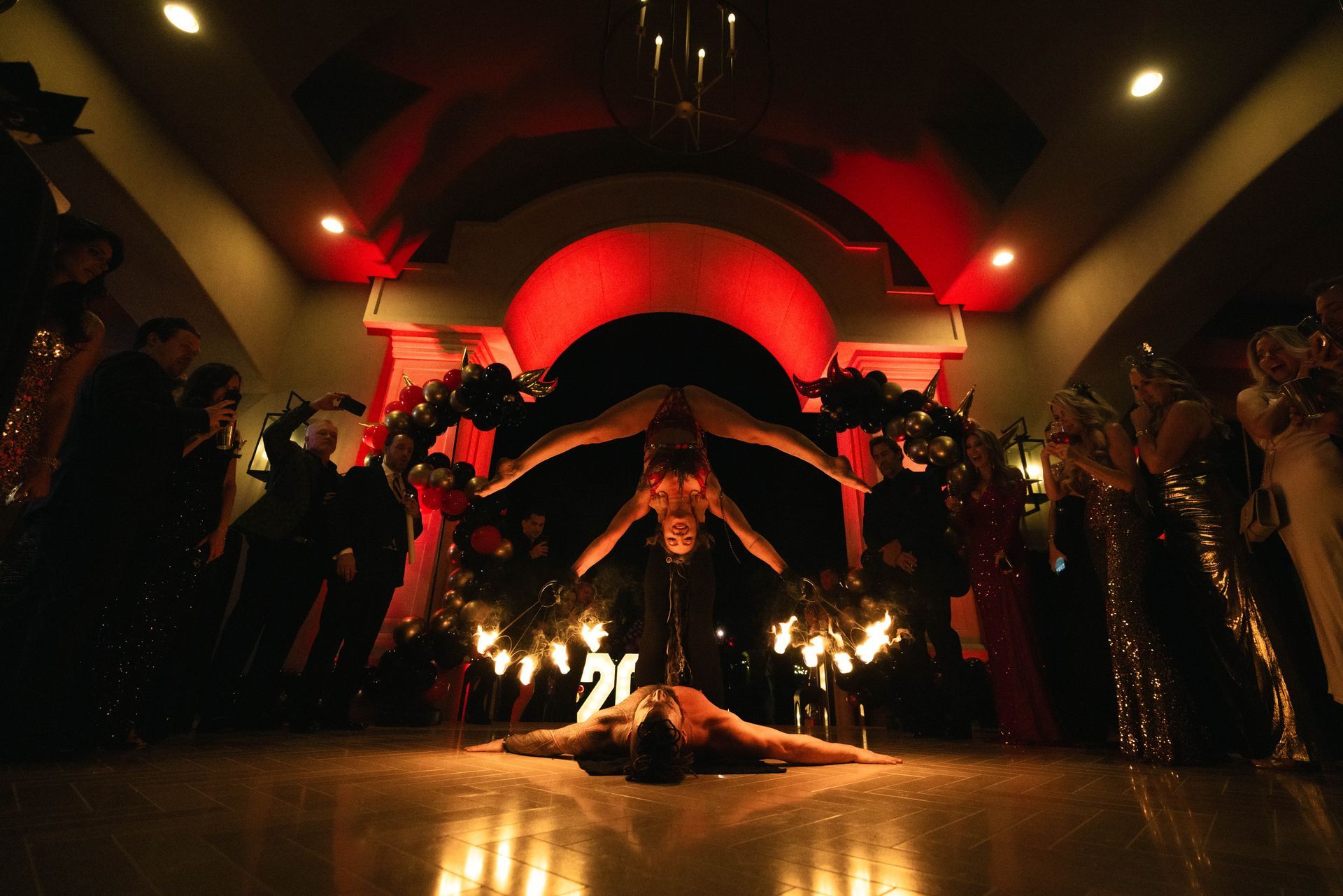 A woman is doing a handstand on the floor in front of a crowd