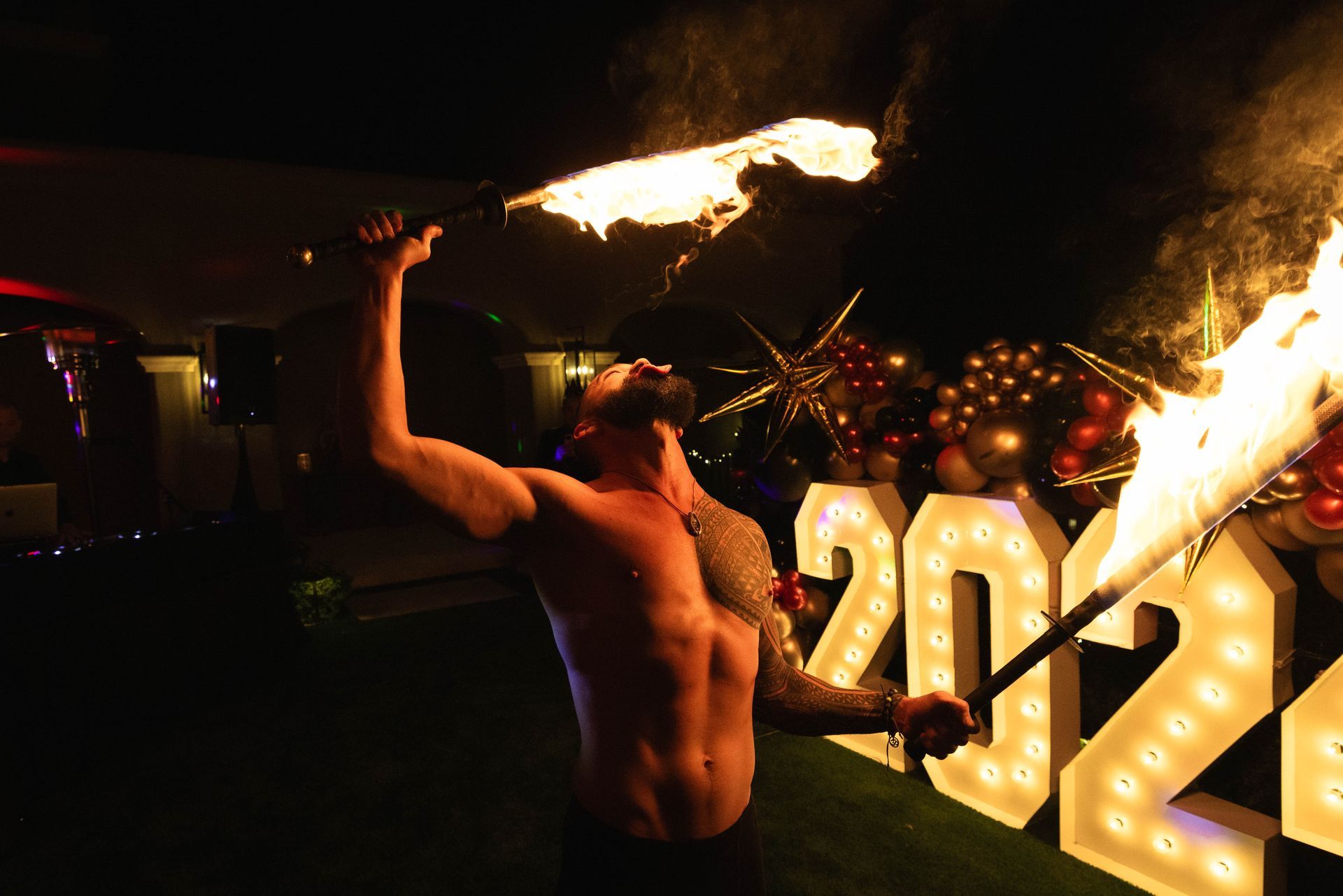 A shirtless man is holding a torch in front of a sign that says 2022.