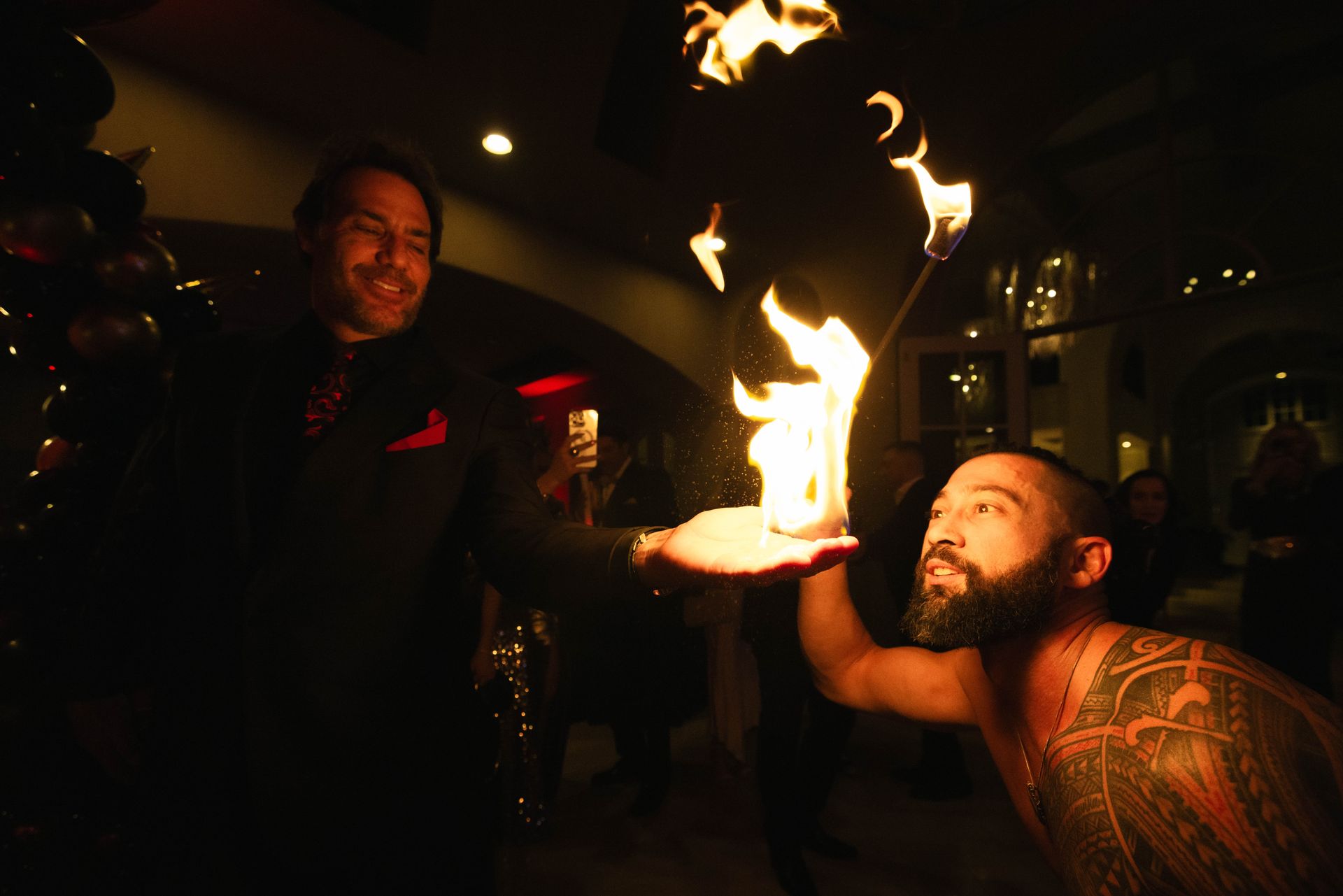 A man with a tattoo on his chest is holding a fire in his hand.