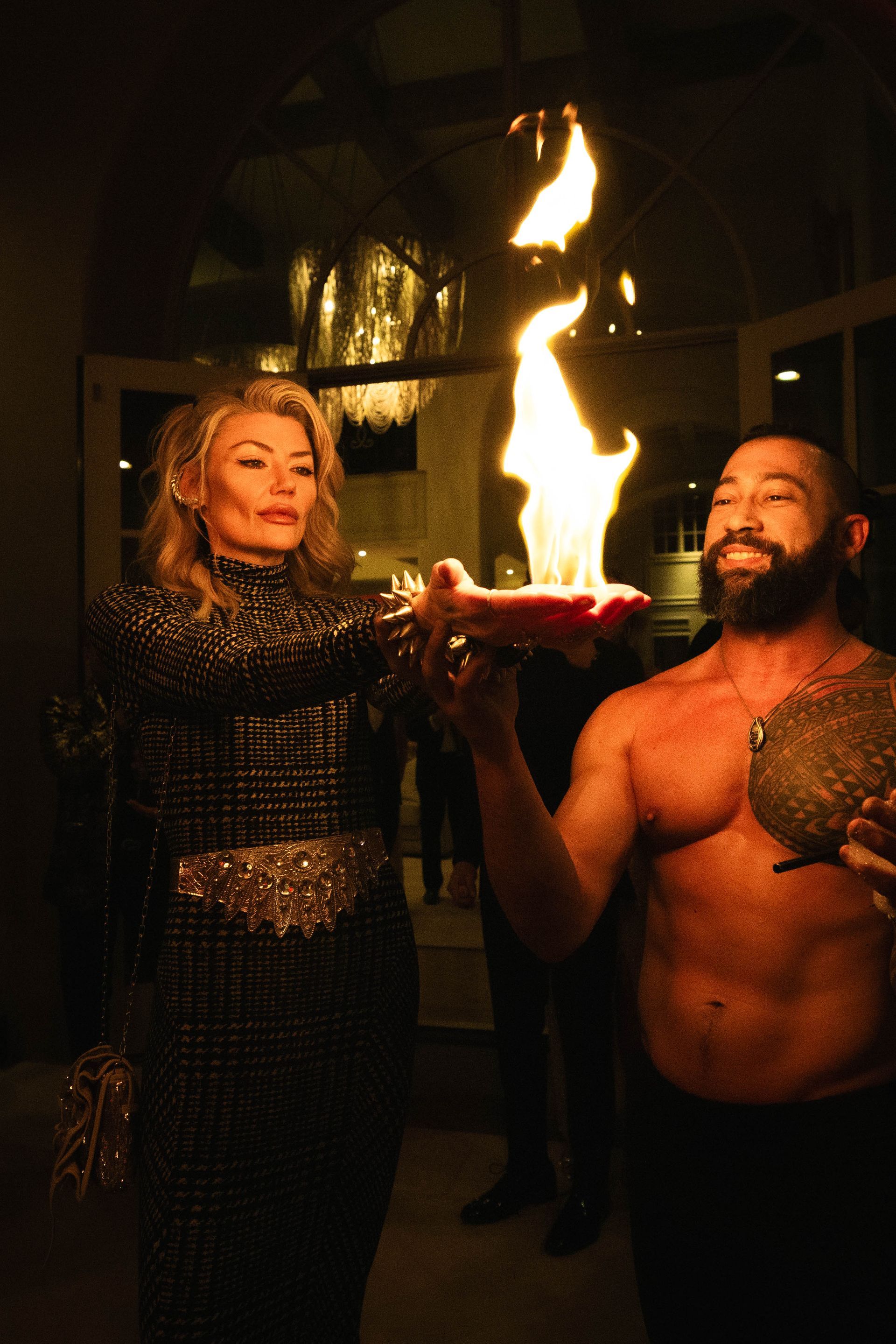 A man and a woman are holding a candle with flames coming out of it.