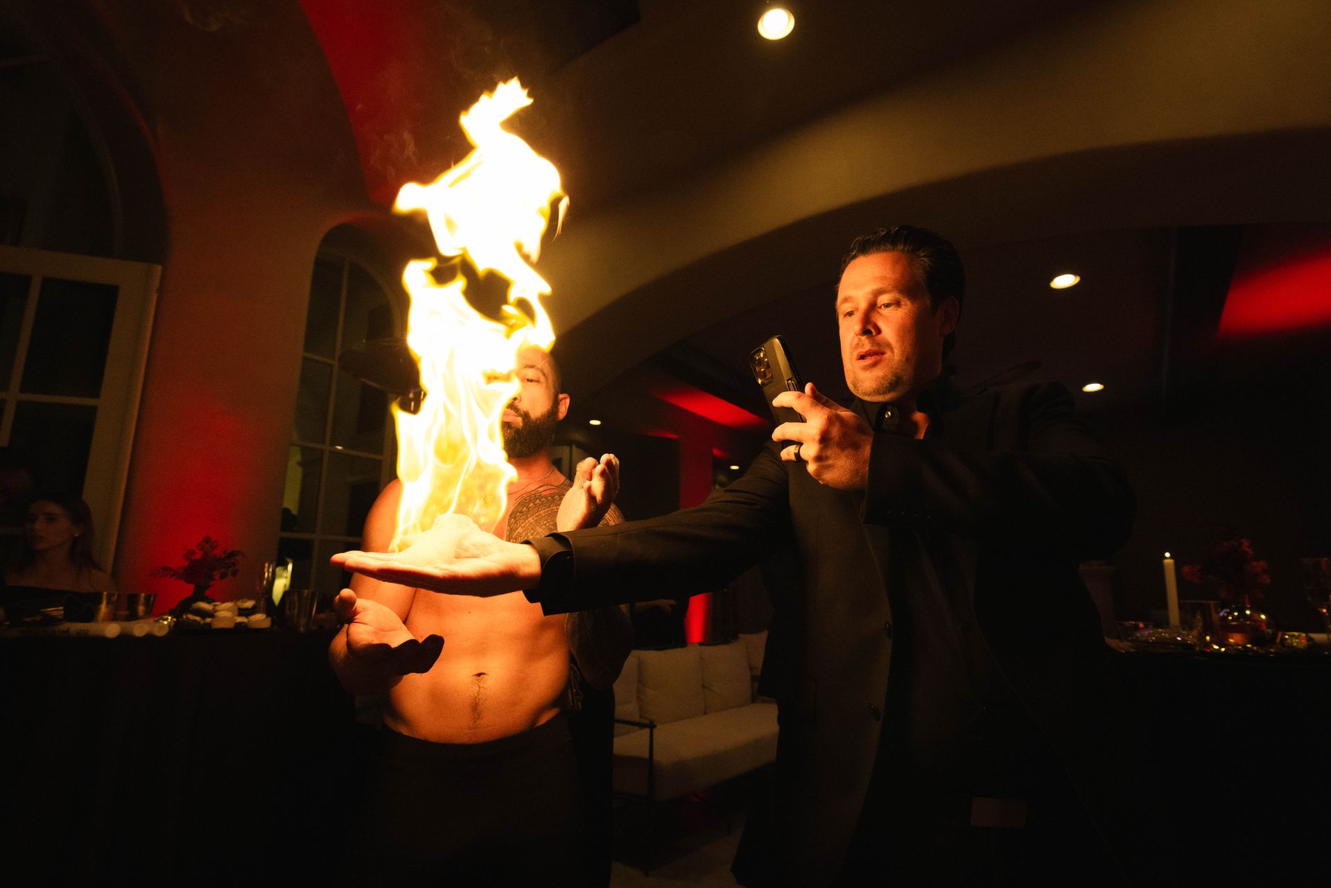 A man is holding a fireball in his hand while another man looks on.