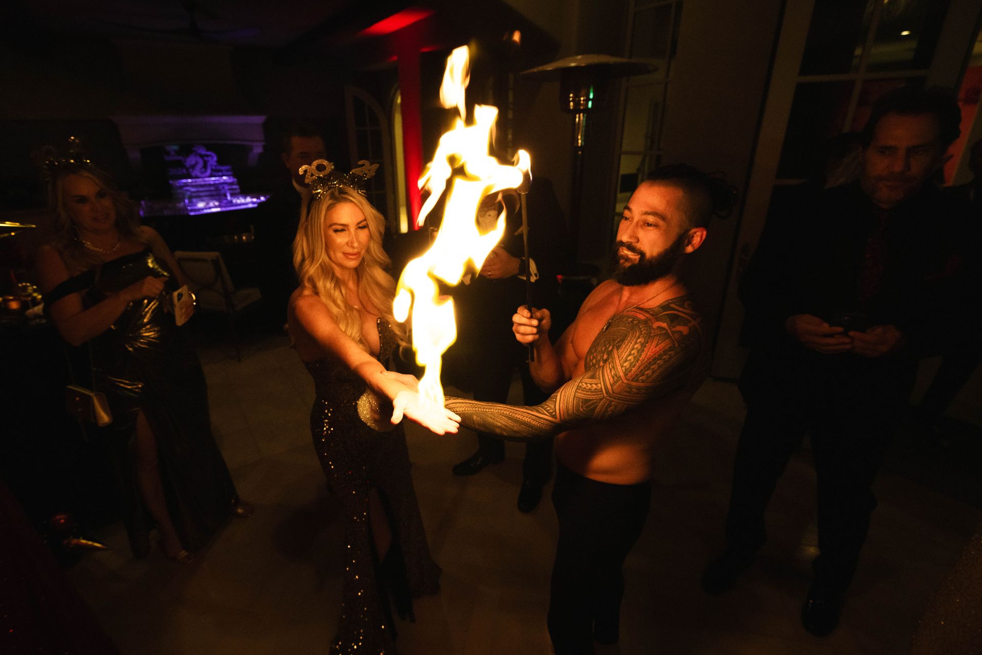 A man and a woman are holding a fire torch in a dark room.