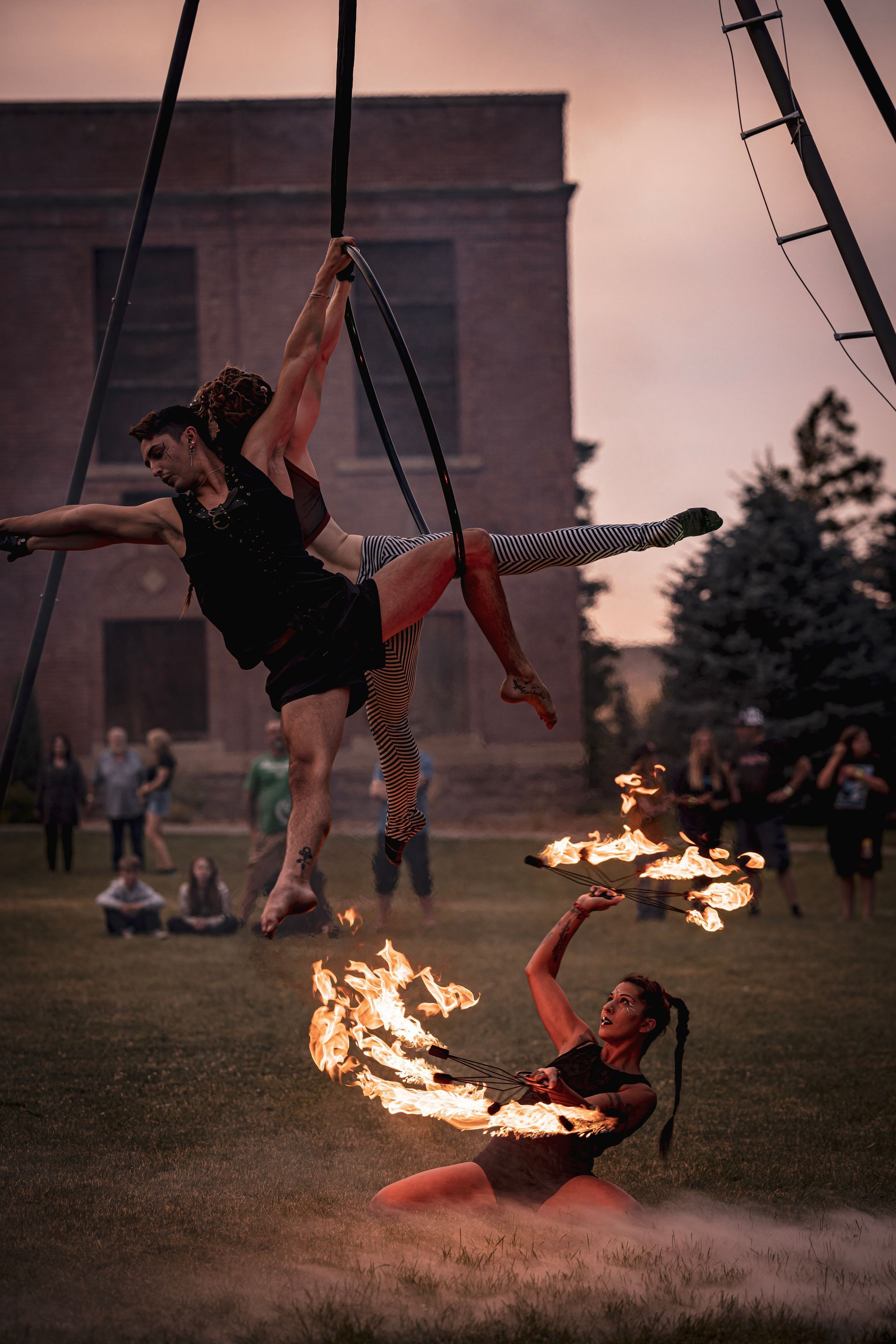 A man and a woman are performing aerial acrobatics with fire.
