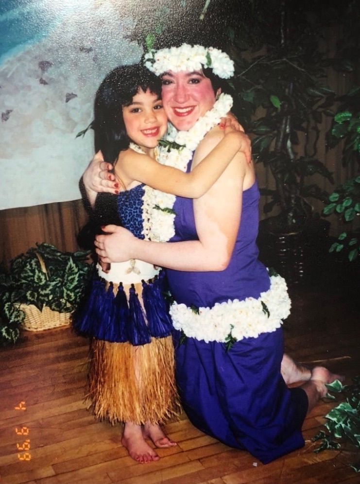 A woman in a purple dress is hugging a little girl