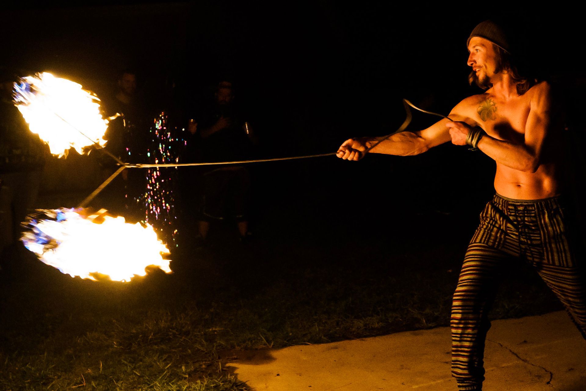 A man is holding a stick with fire coming out of it.