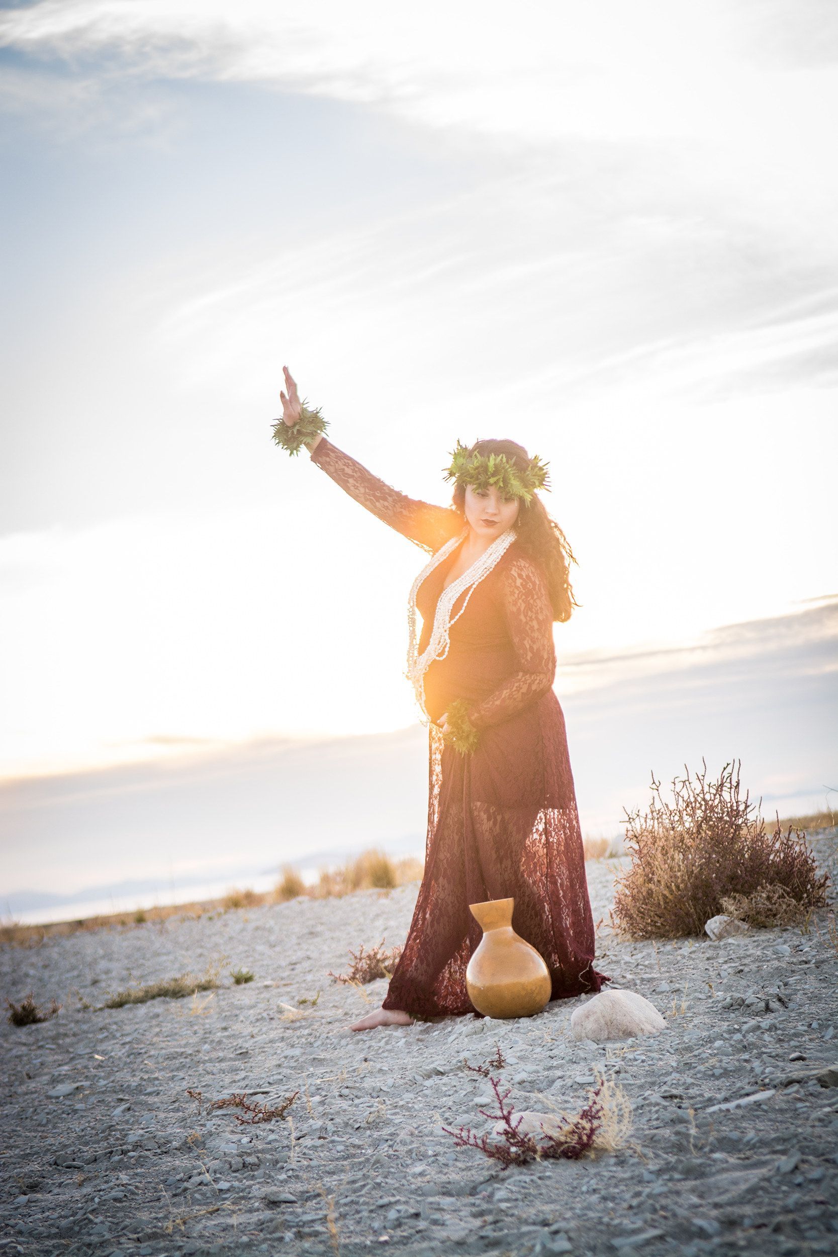 A woman is standing on a rocky beach holding a vase.