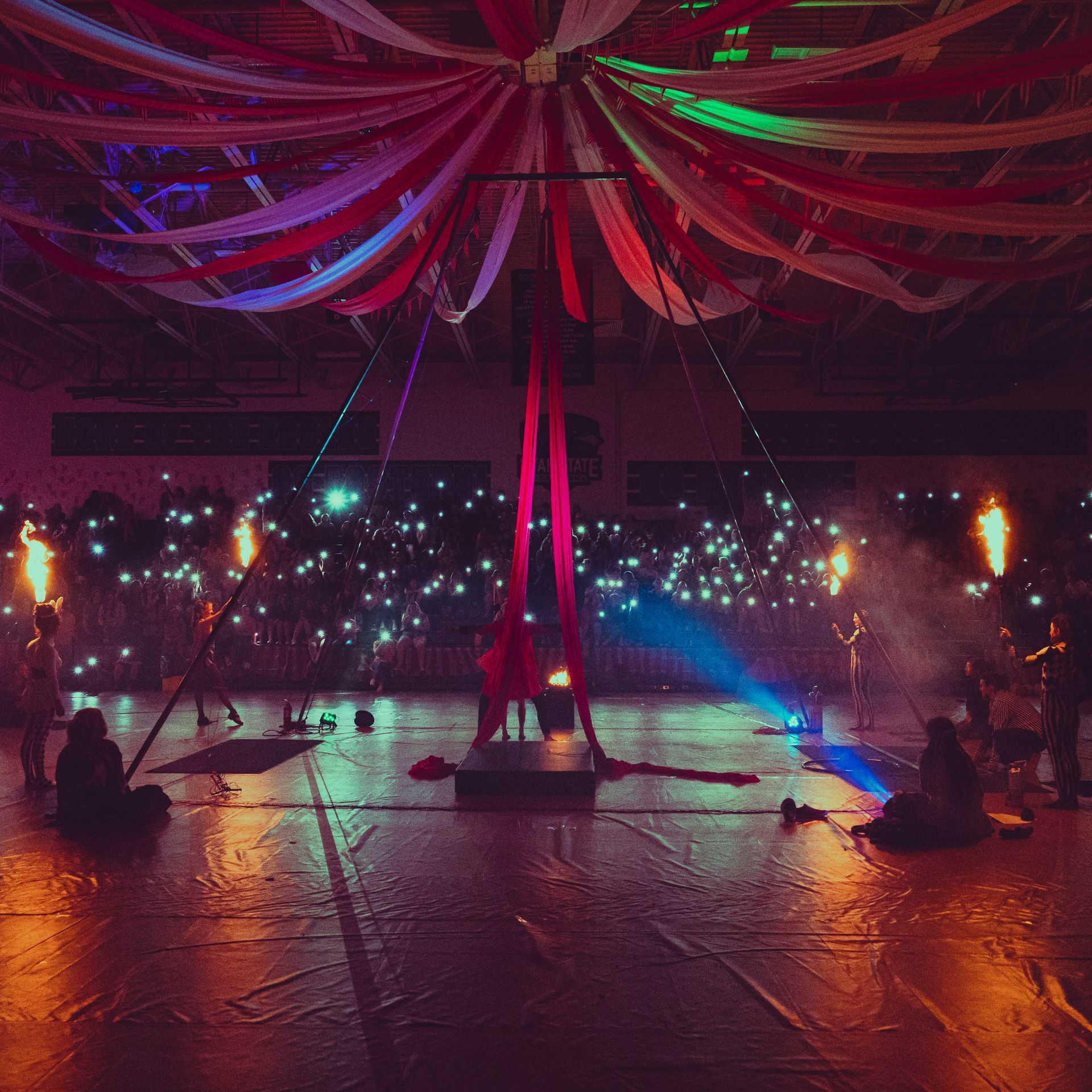 A group of people are sitting on the floor in a dark room watching a performance