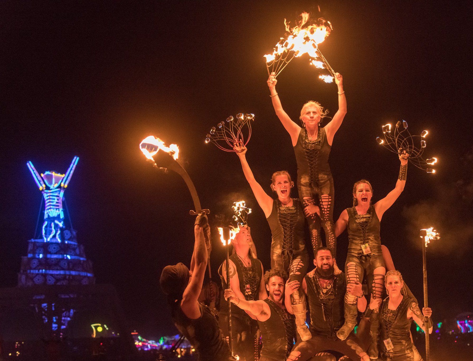 A group of people are standing on top of each other holding flaming torches