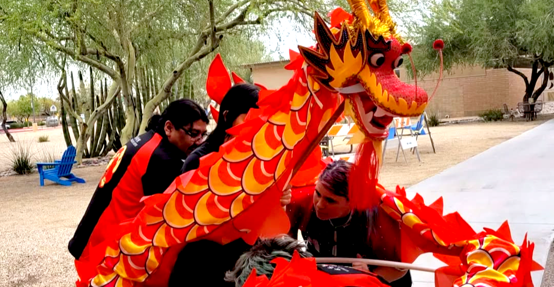 A group of people are standing around a red and yellow dragon.
