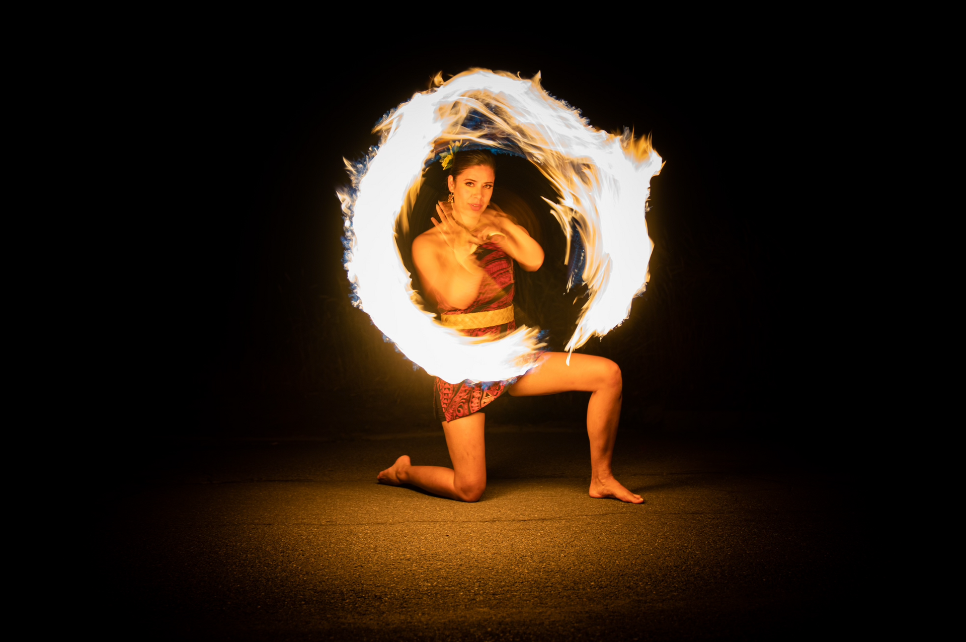 A woman is kneeling down in front of a circle of fire.