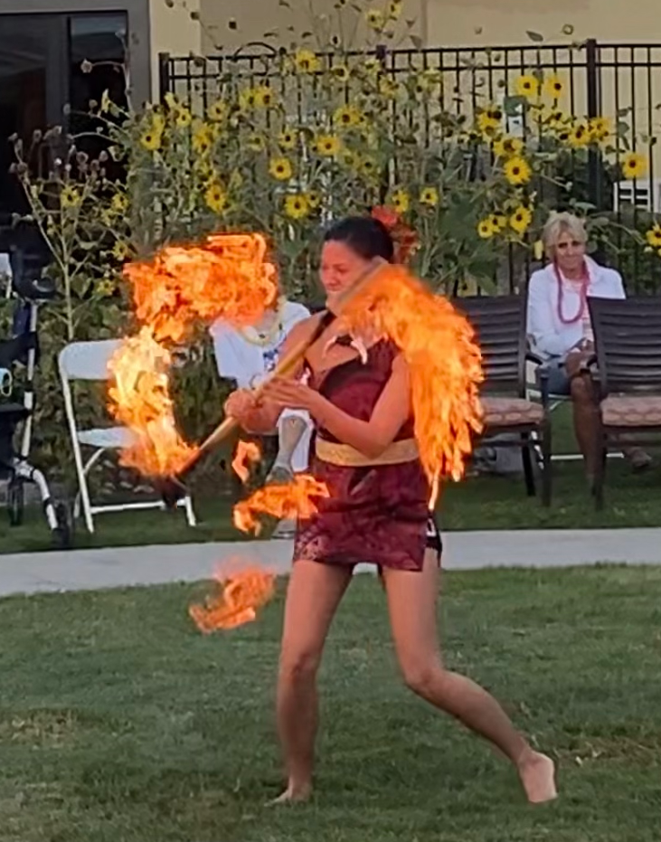 A woman in a costume is holding a stick of fire