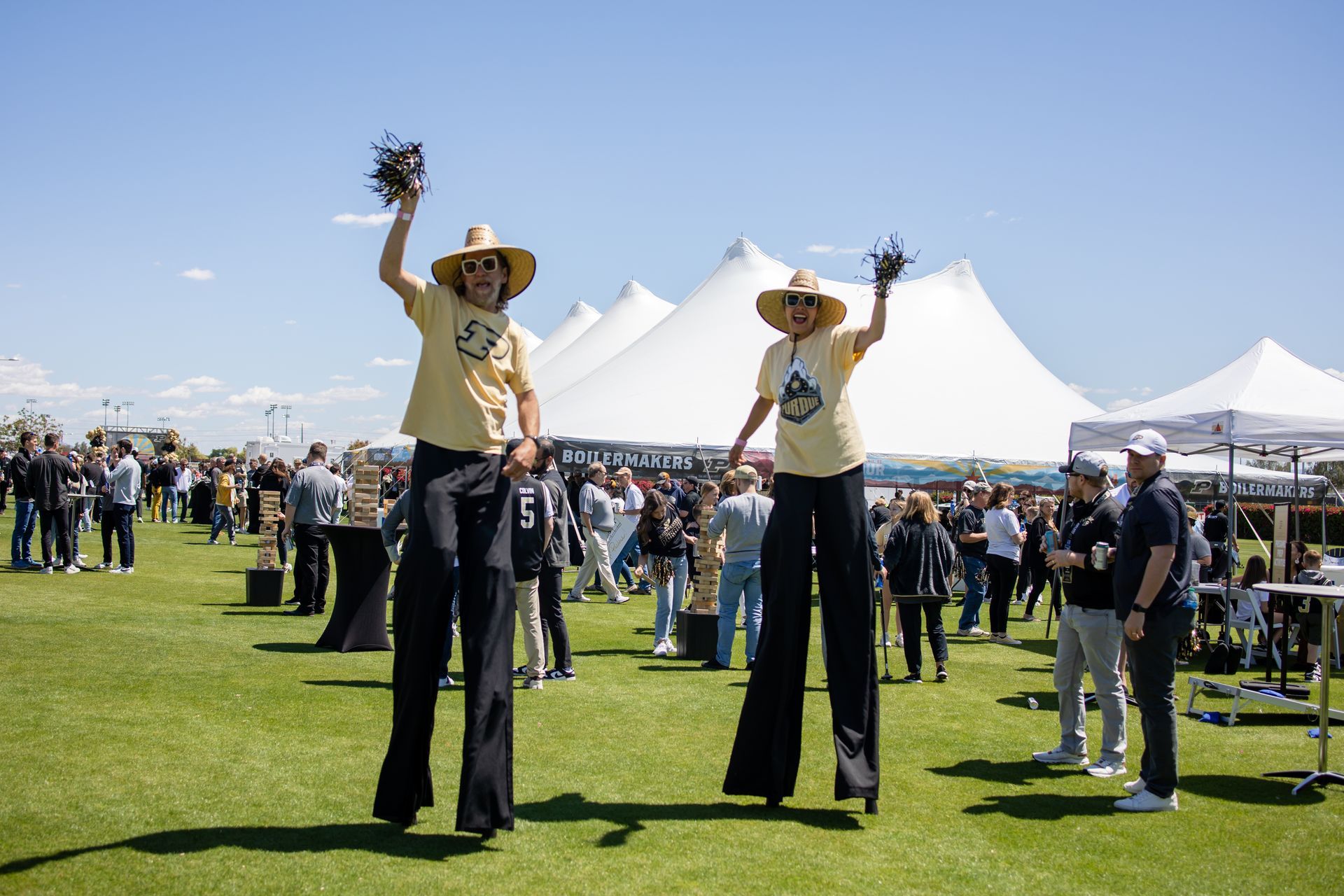 A couple of people standing on stilts in a field.