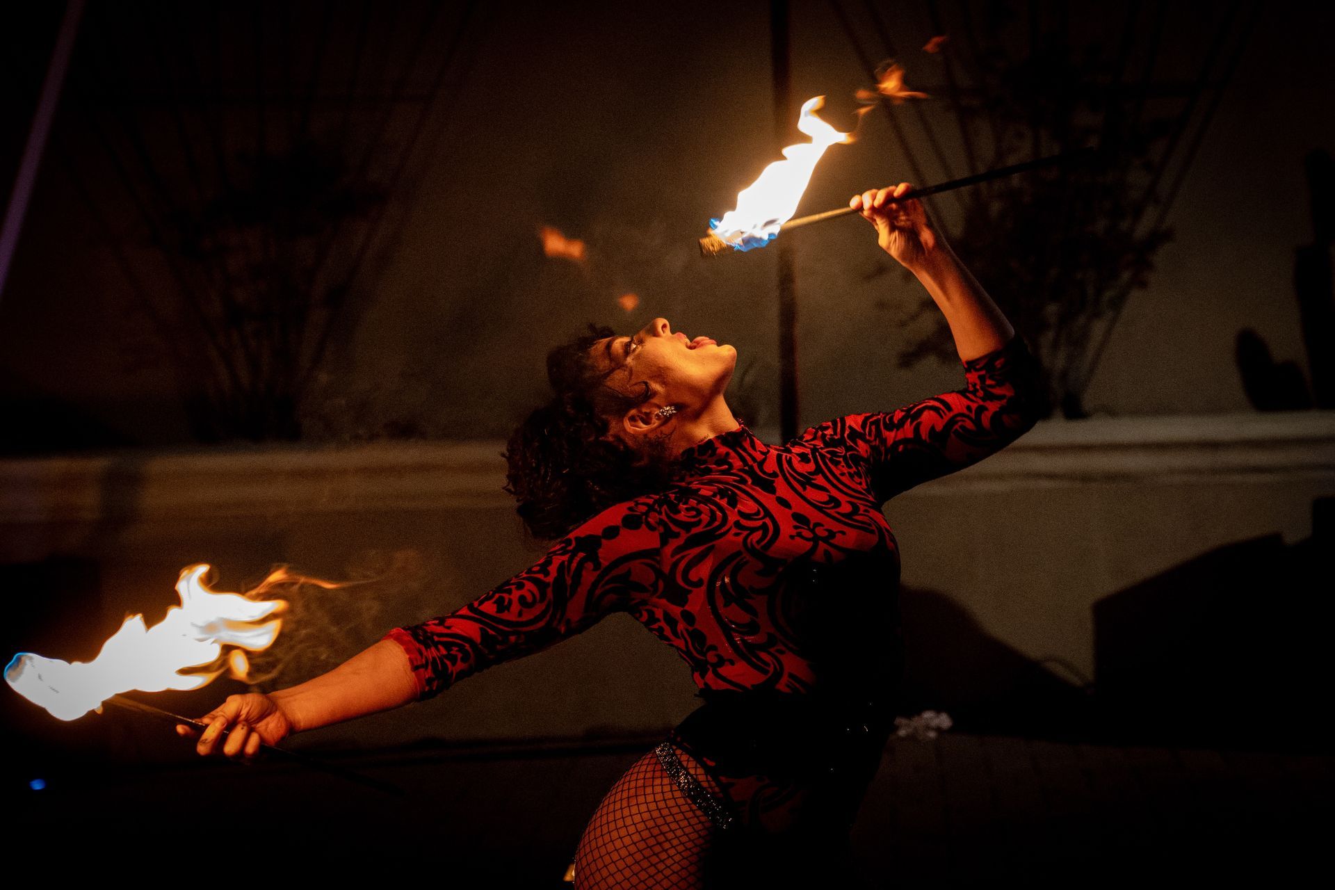 A woman is holding a stick with fire coming out of it.
