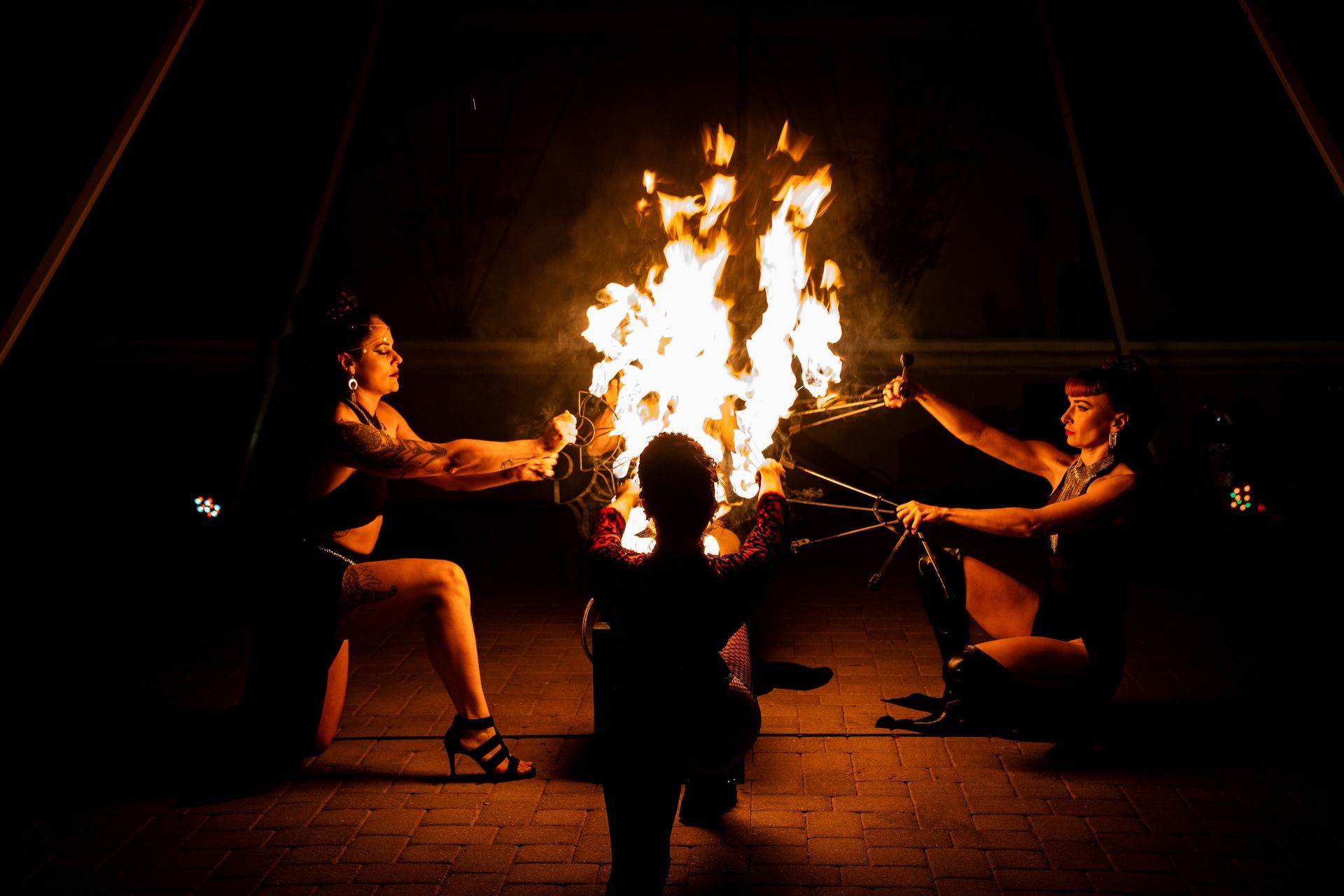 A group of people are standing around a fire pit at night.