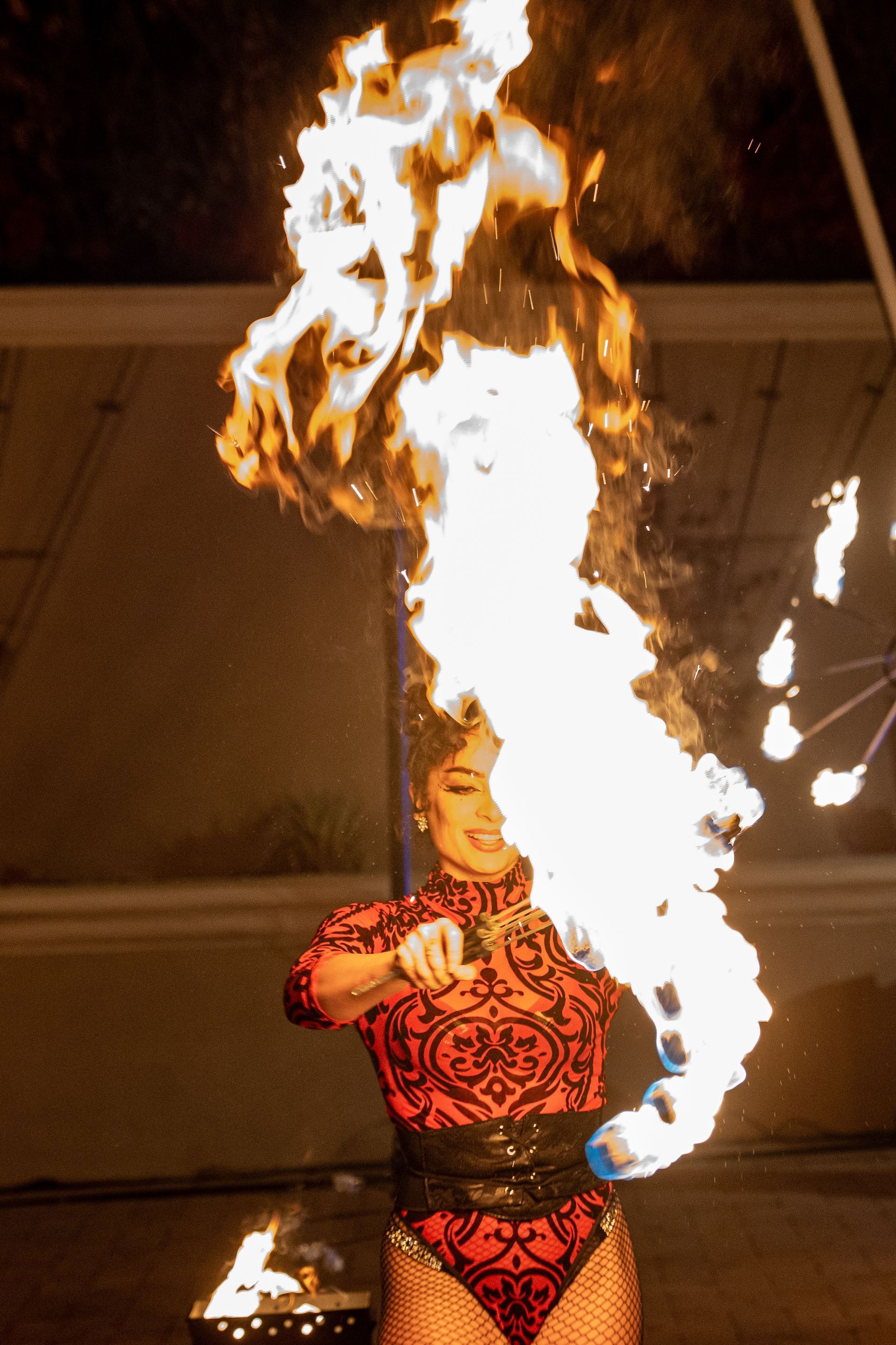 A woman in a red bodysuit is holding a torch with flames coming out of it.