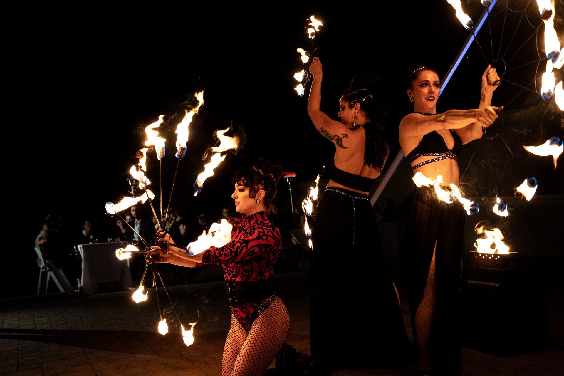 A group of women are performing a fire show at night.