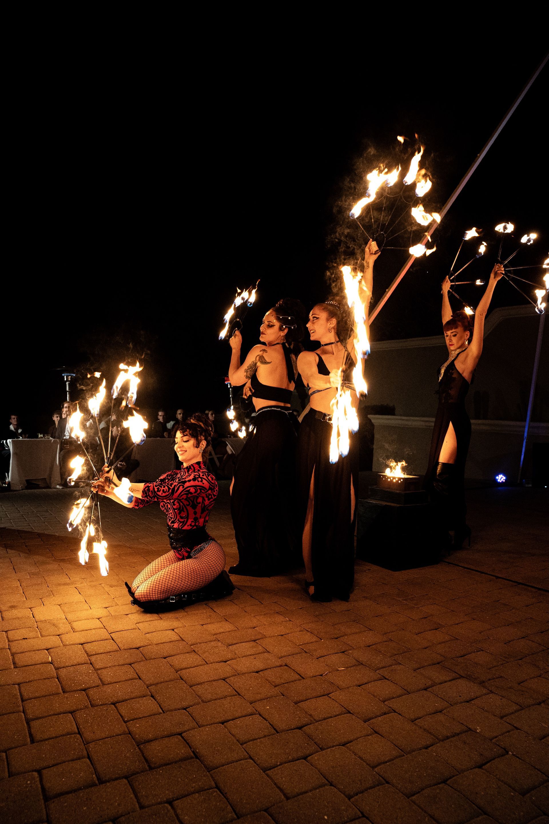 A group of women are performing a fire show at night.
