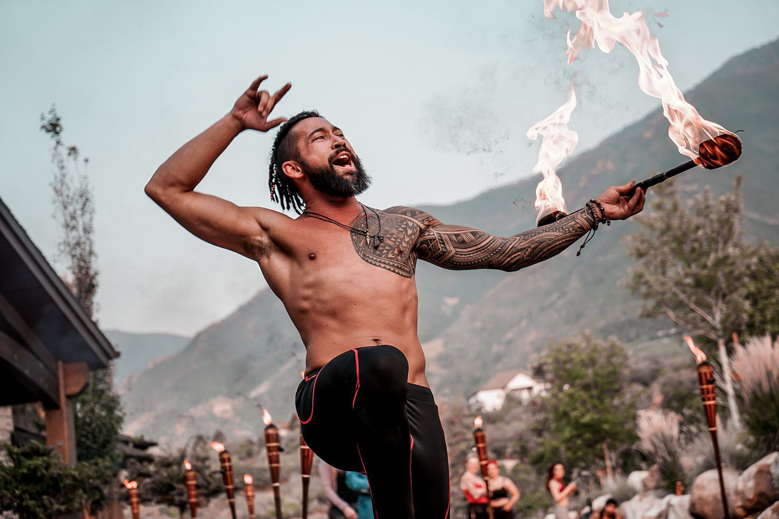 A shirtless man is juggling a torch with flames coming out of it.