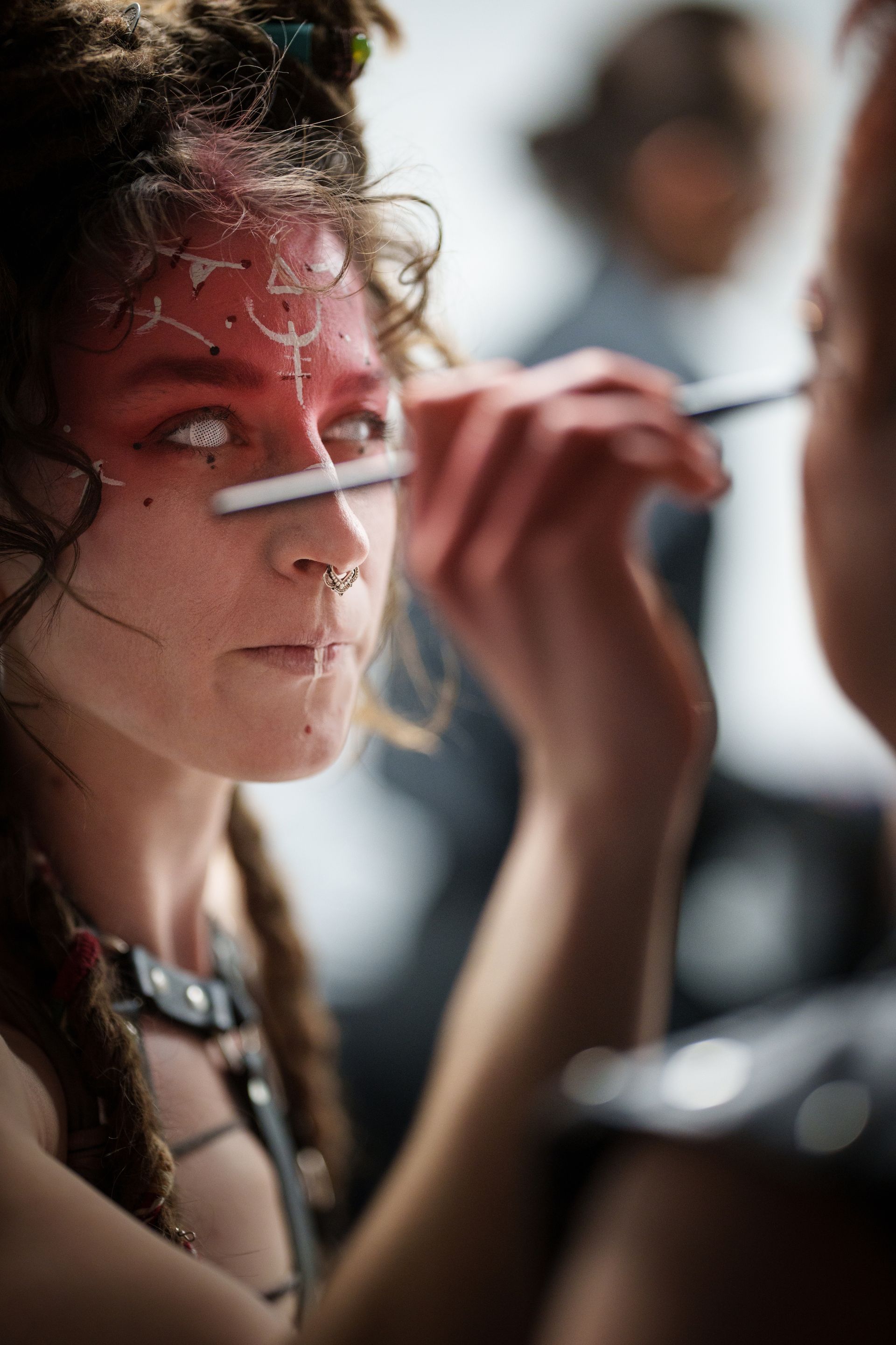 A woman is getting her face painted by another woman