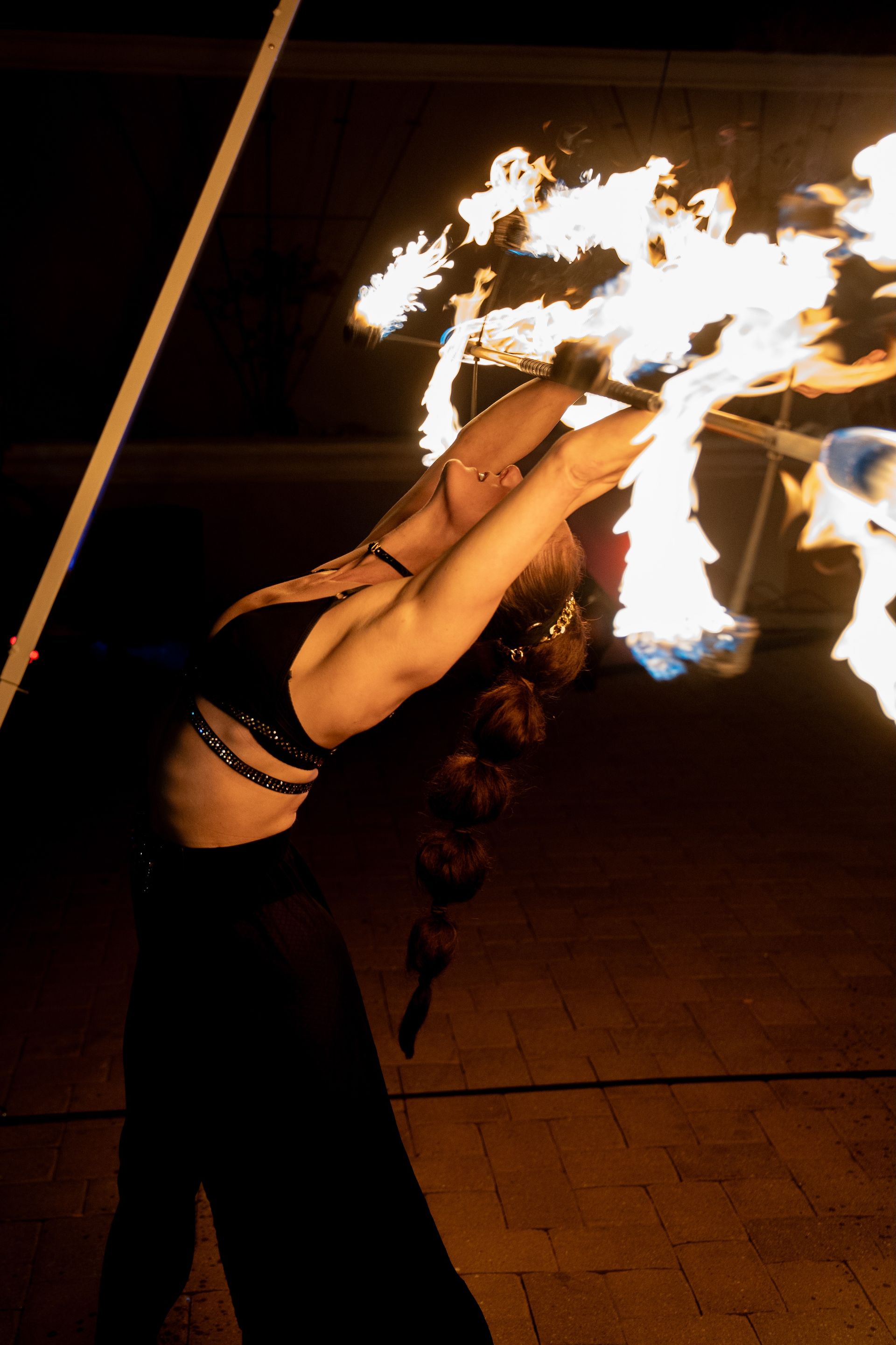 A woman is holding a stick with fire coming out of it.