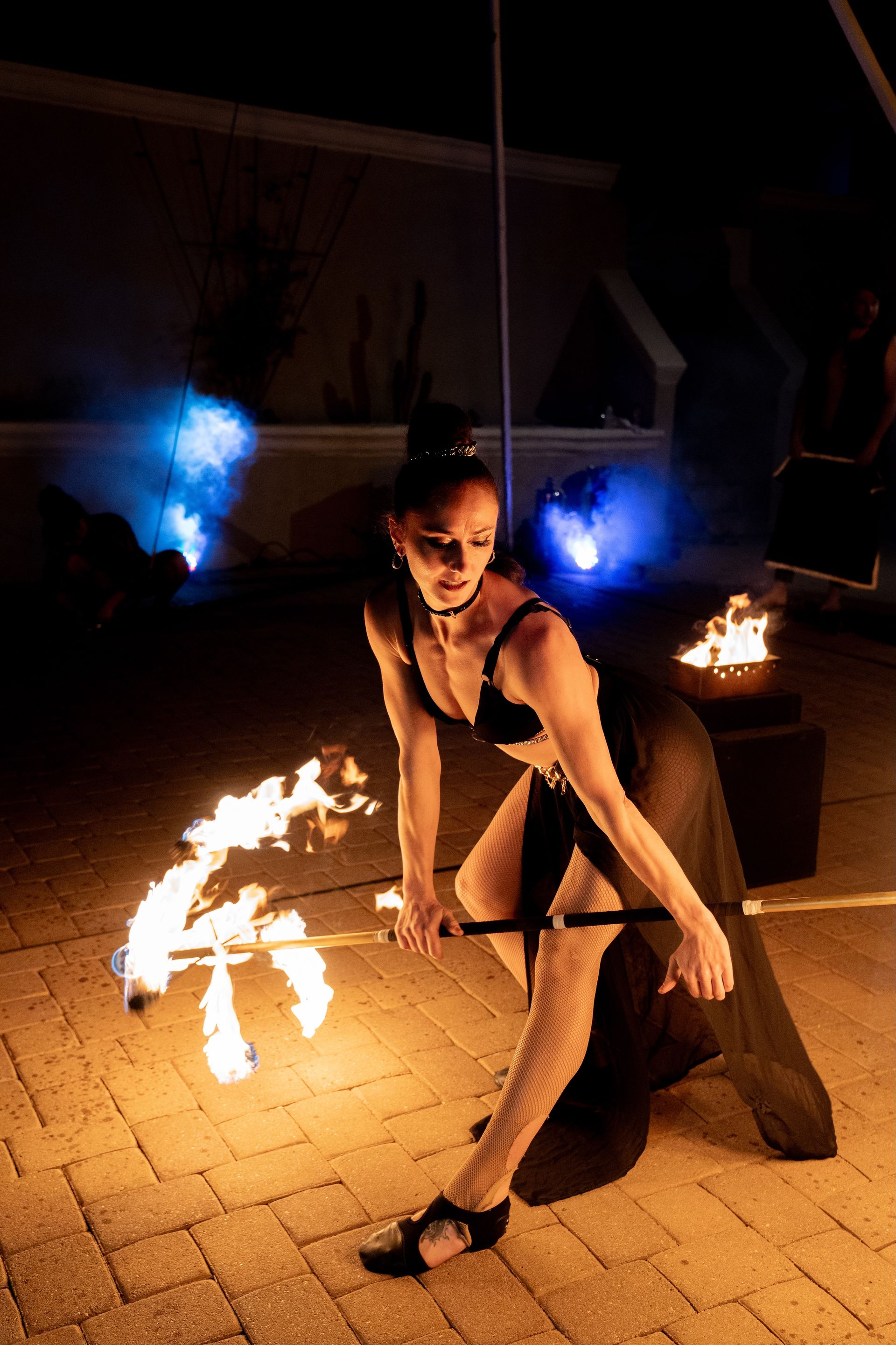 A woman bending over while performing with a dragon staff with stage lights.