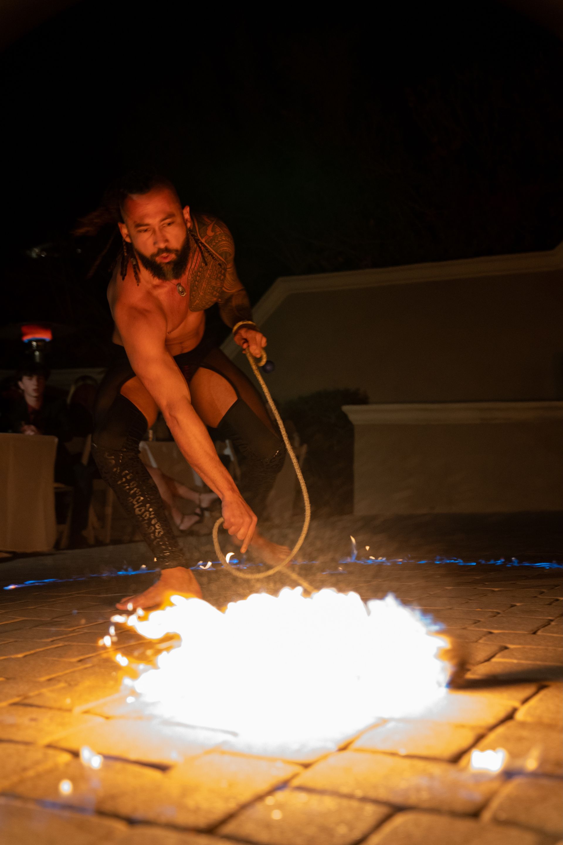 A man is holding a rope in front of a fire.