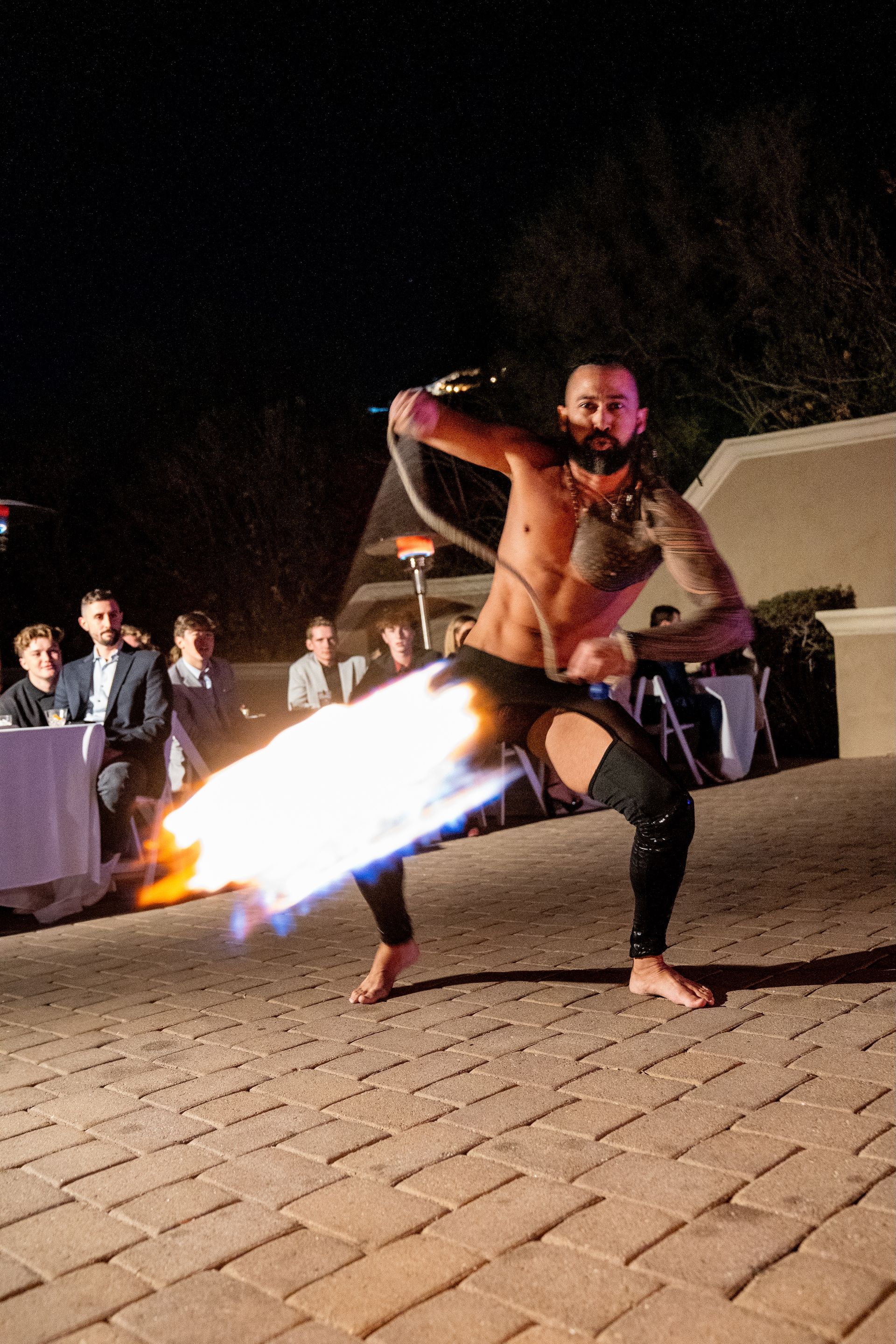 A man is holding a fire torch in his hand while people watch.