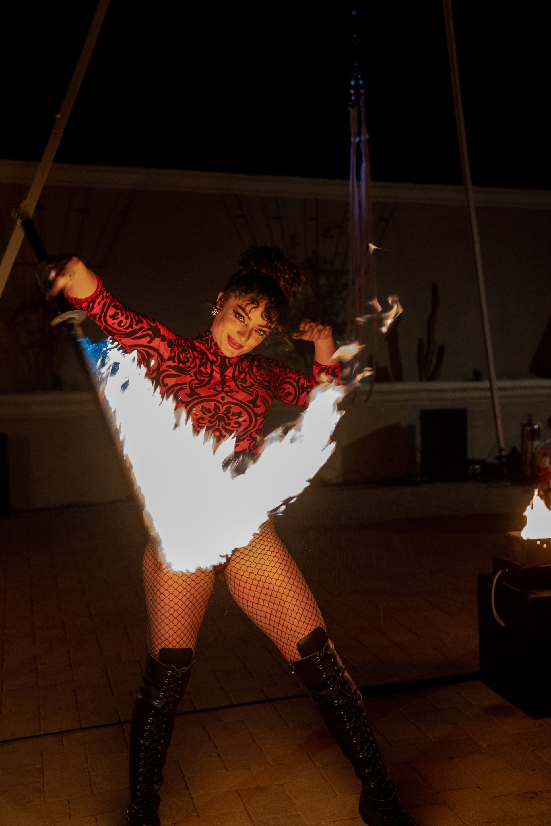 A smiling woman performing with a fire sword.