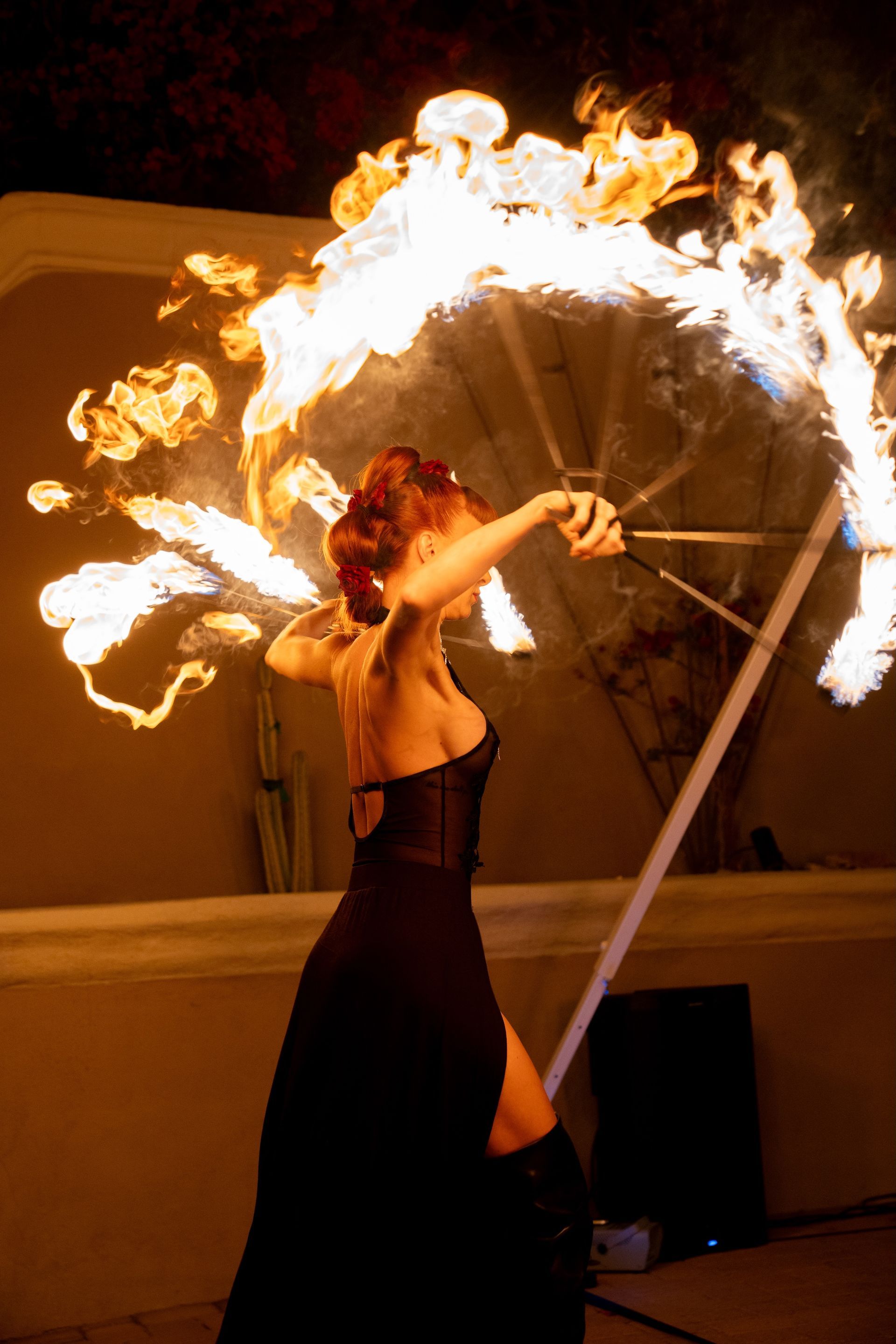 A woman in a black dress is holding a fan of fire.