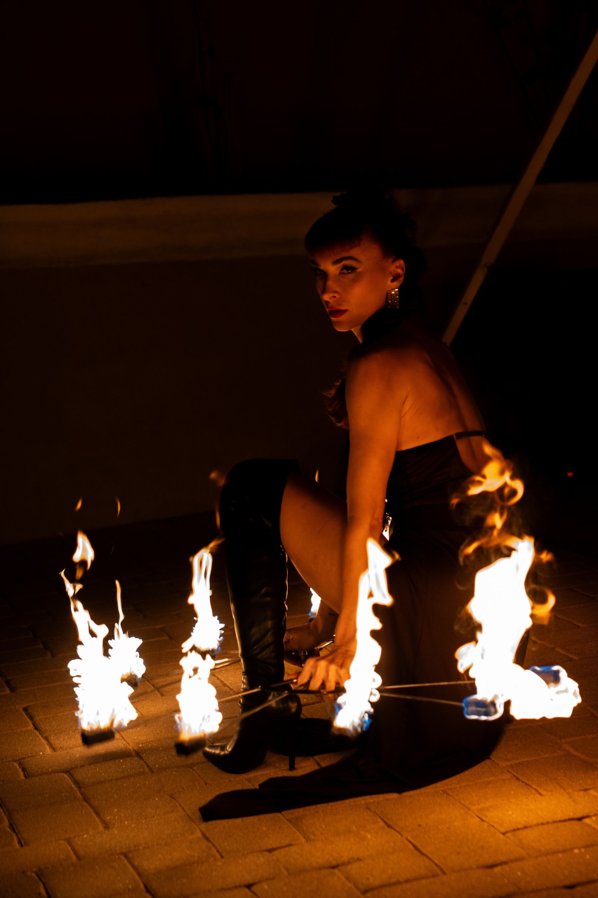 A woman in a black dress is kneeling down in front of a fire display.