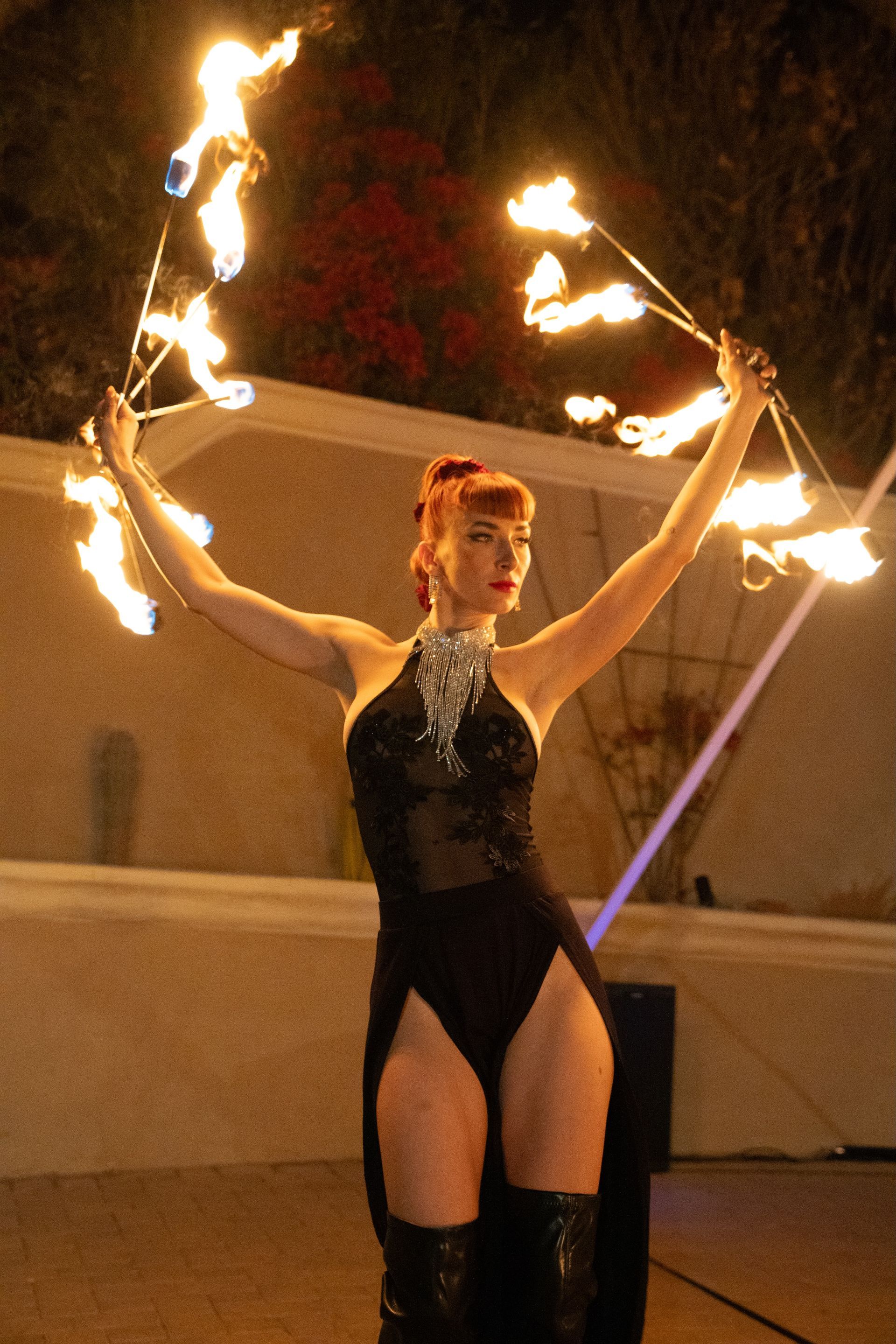 A woman in a black bodysuit is holding a bunch of fire sticks