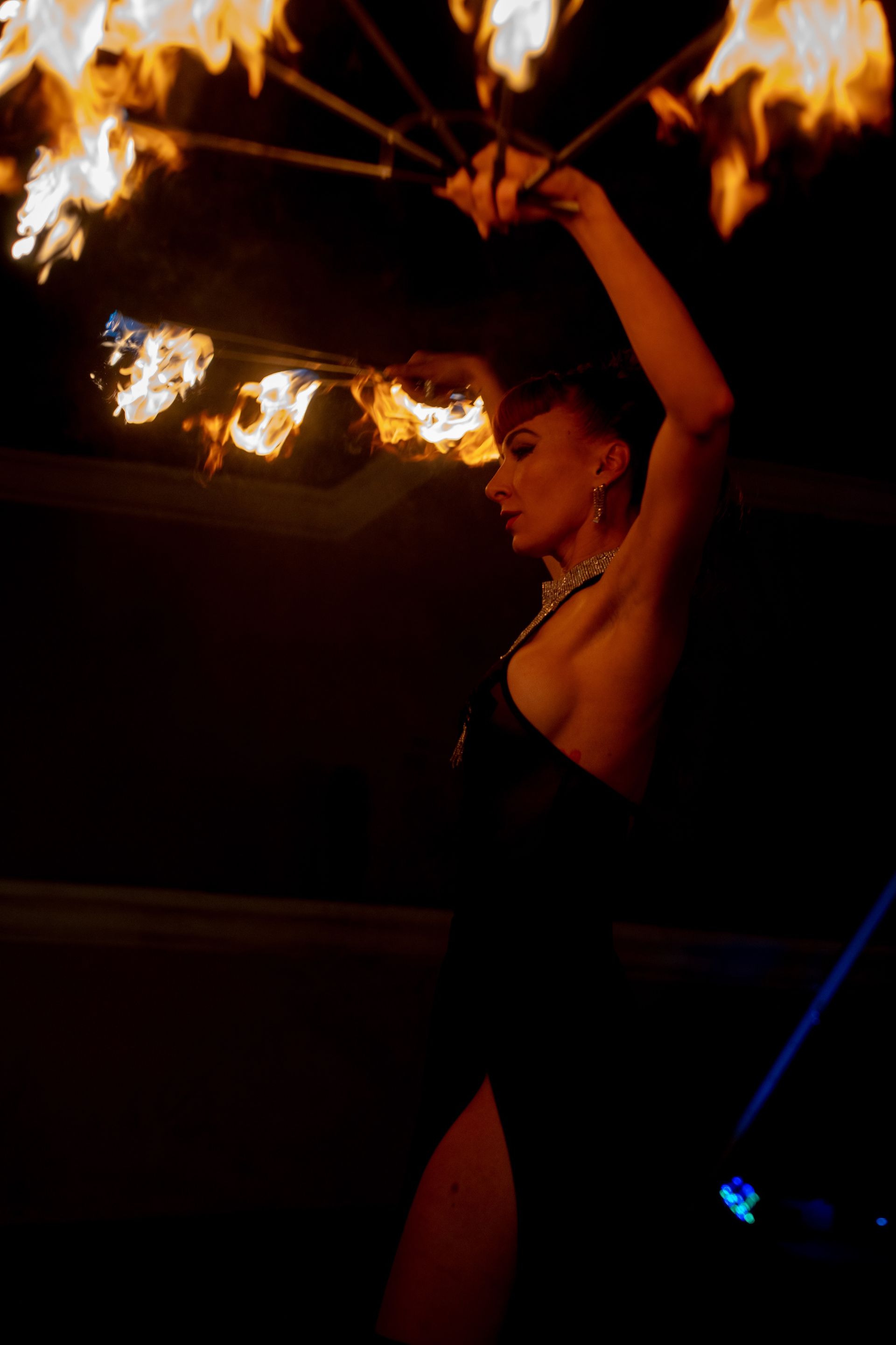 A woman in a black dress is holding a fan of fire.